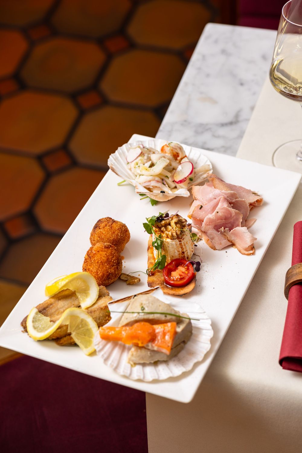 A series of elegant appetizer plates featuring seafood and garnishes served on white rectangular dishes at a fine dining restaurant.