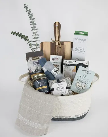 A luxury spa gift set with bath products arranged in a white round tray featuring soaps, lotions, and eucalyptus stems.