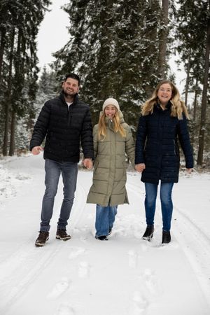 A group of people walking together on a snowy winter path through evergreen trees.
