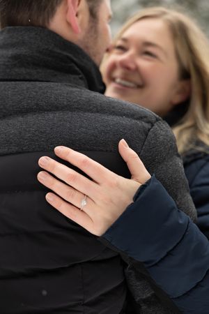 Close-up sequence showing a hand with an engagement ring embracing someone wearing a dark coat.