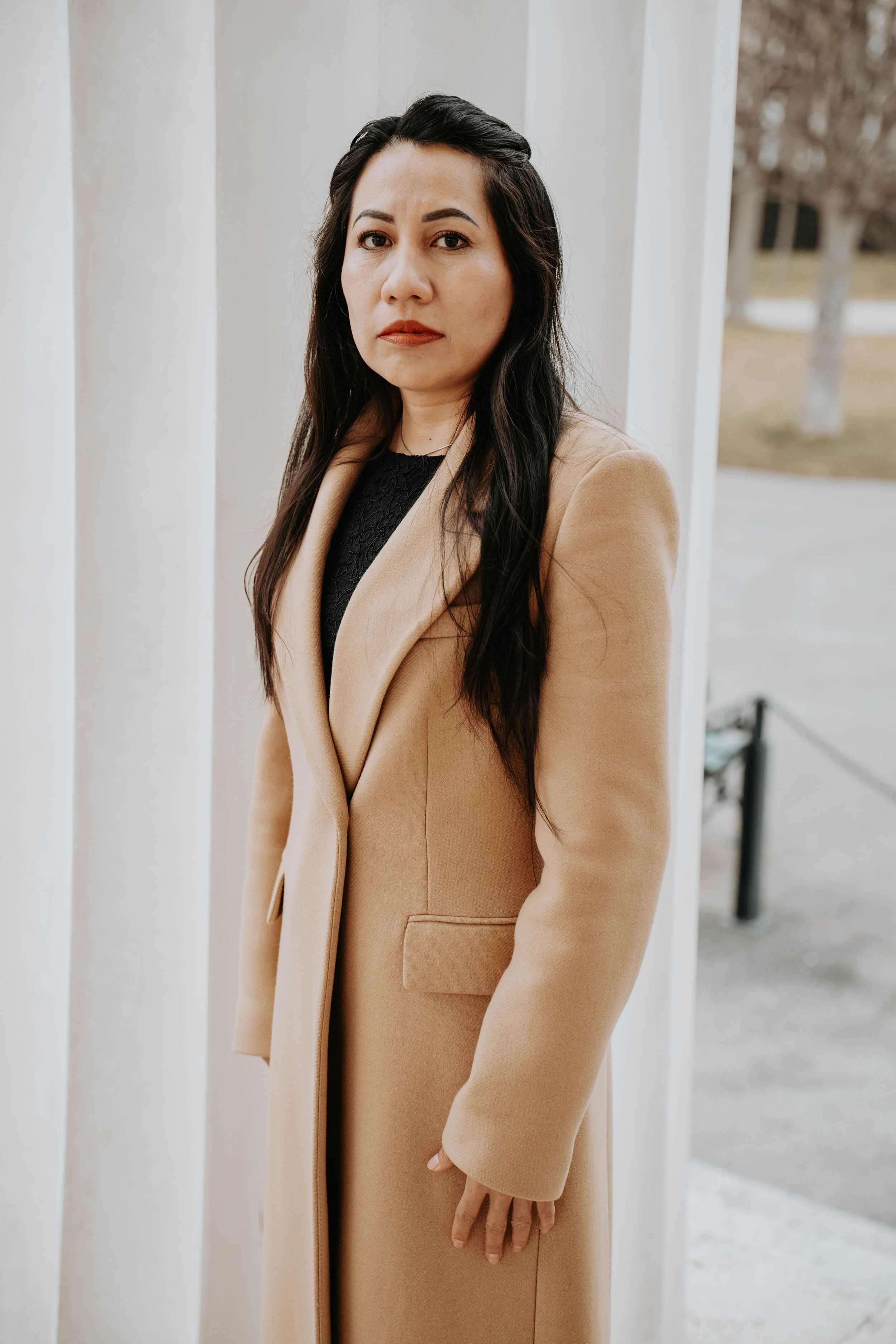 A woman in a camel-colored coat poses outdoors in a series of fashion portraits.