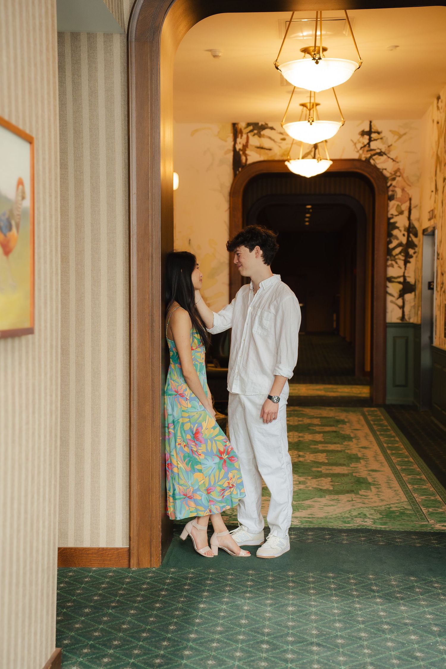 A playful sequence showing two people dancing in an elegant hallway with green carpeting.