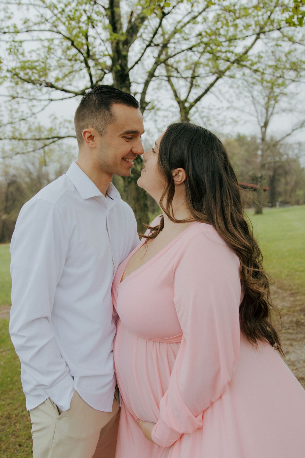 A couple in coordinating outfits share a tender moment in a spring garden setting.
