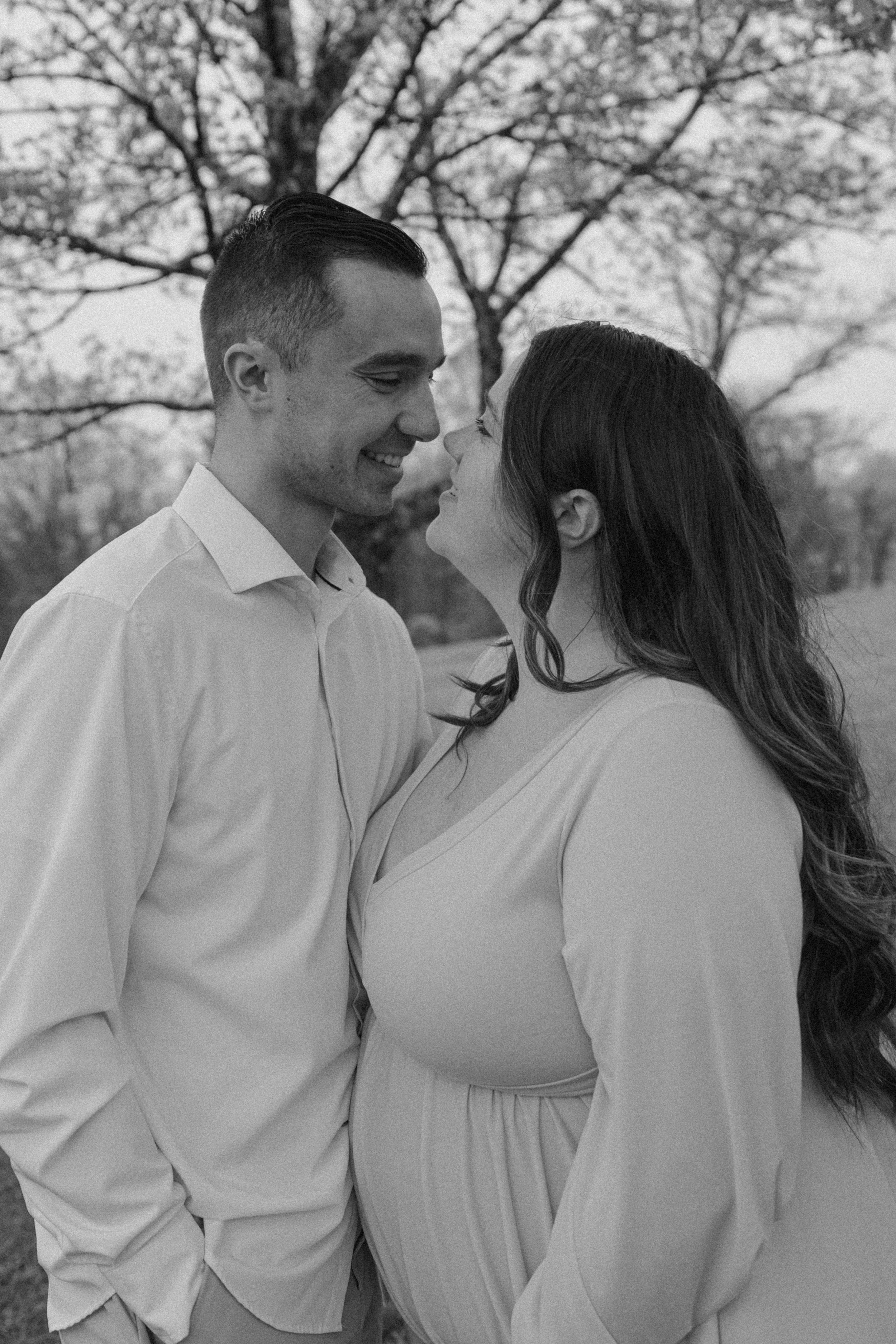 A romantic black and white portrait of a couple sharing an intimate moment outdoors.