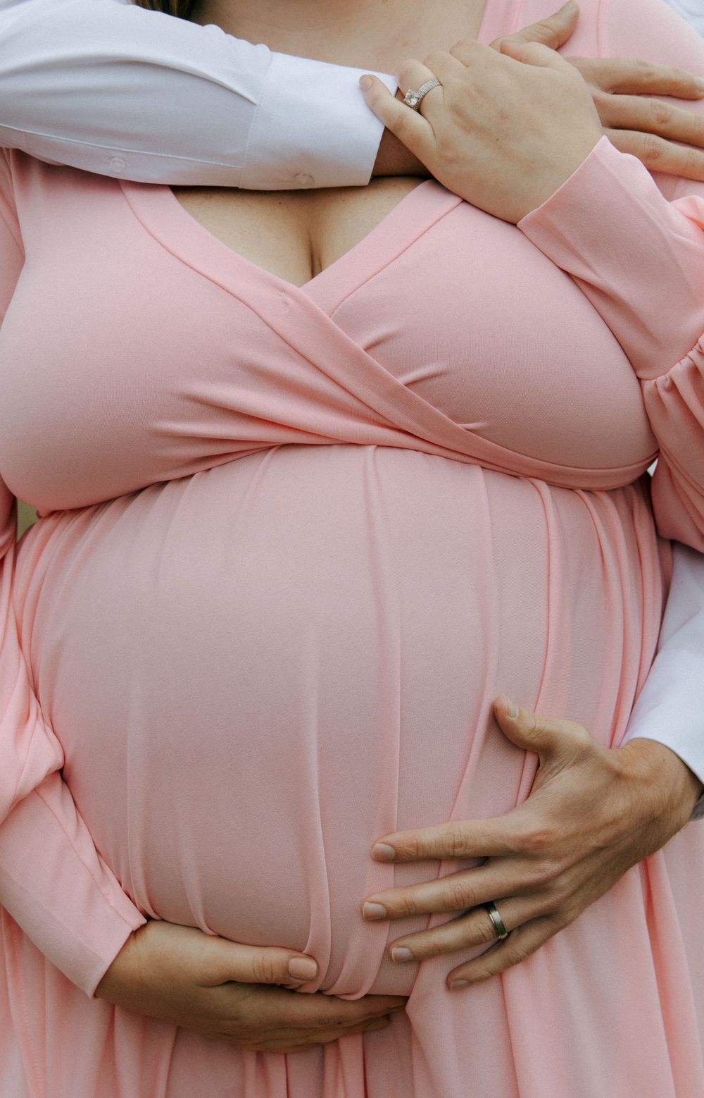 Close-up shots highlighting a pregnant belly in a soft pink maternity dress.