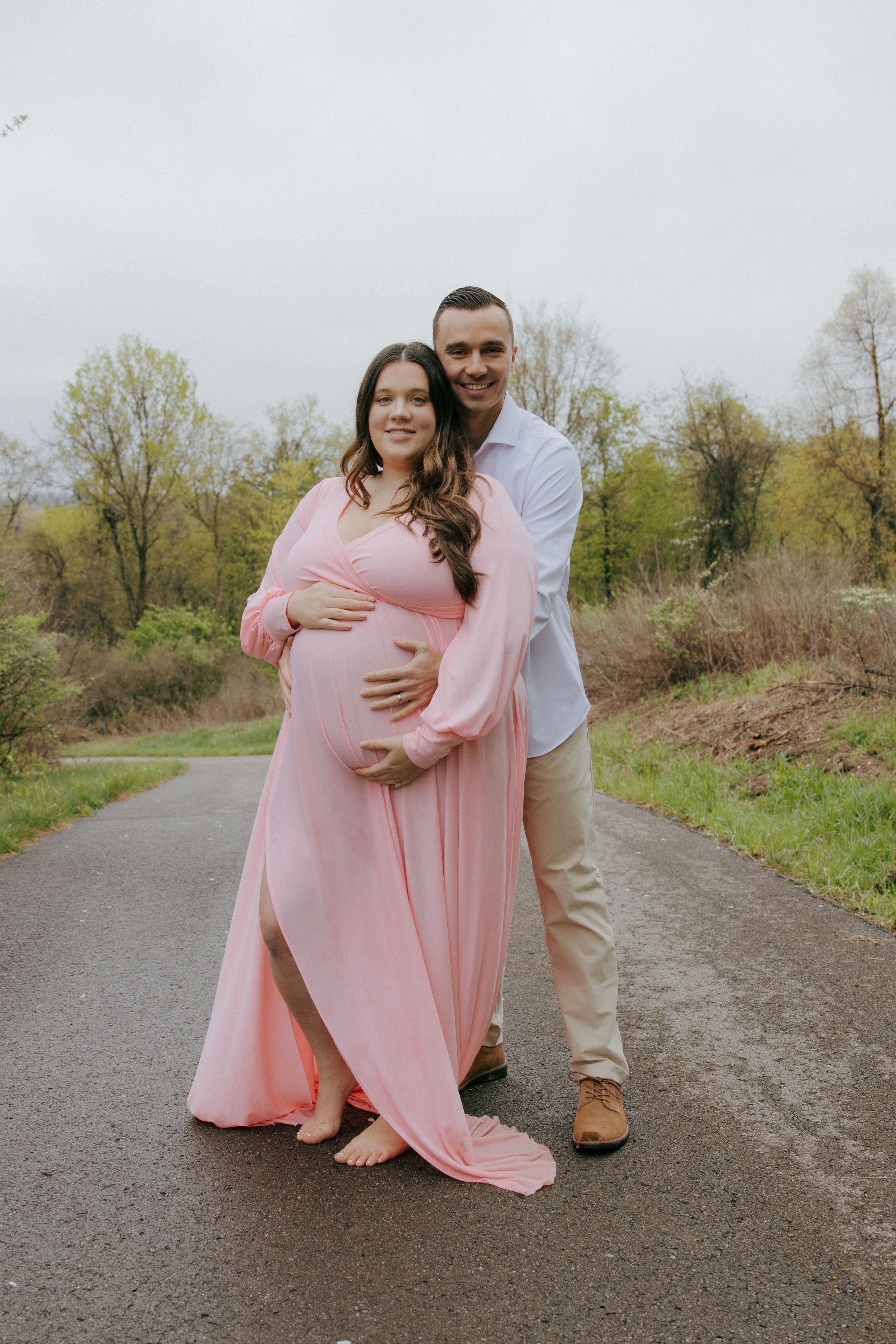 A couple poses together on a path during their outdoor maternity session.