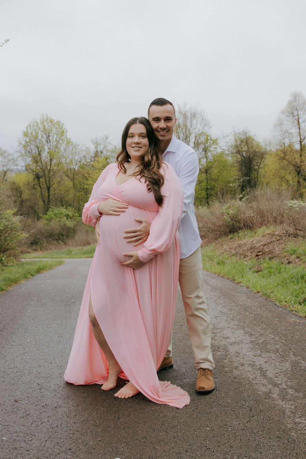 A couple poses together on a path during their outdoor maternity session.