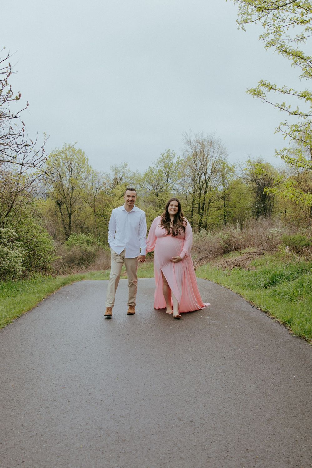 A couple walks together on a path surrounded by spring foliage.