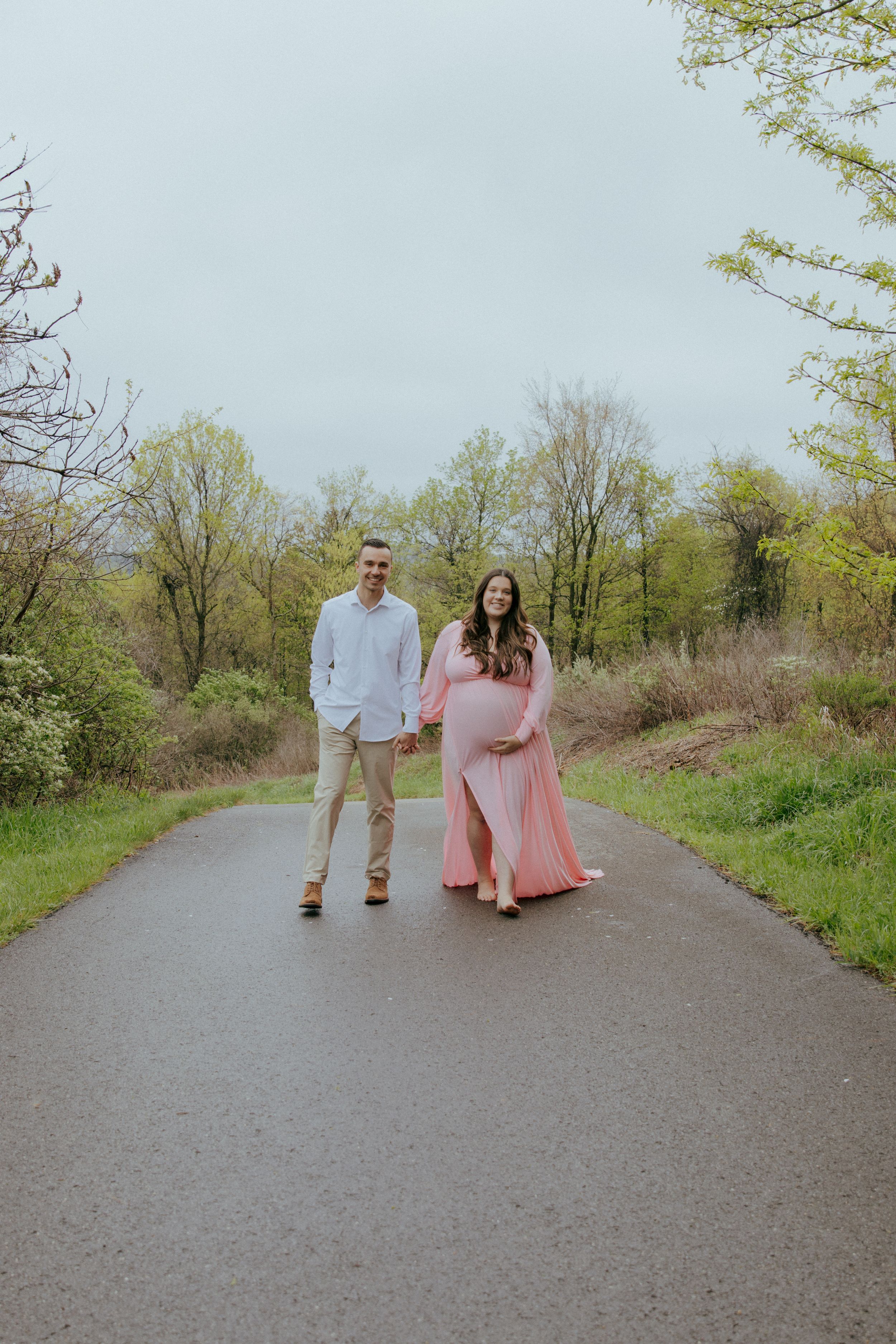 A couple walks together on a path surrounded by spring foliage.