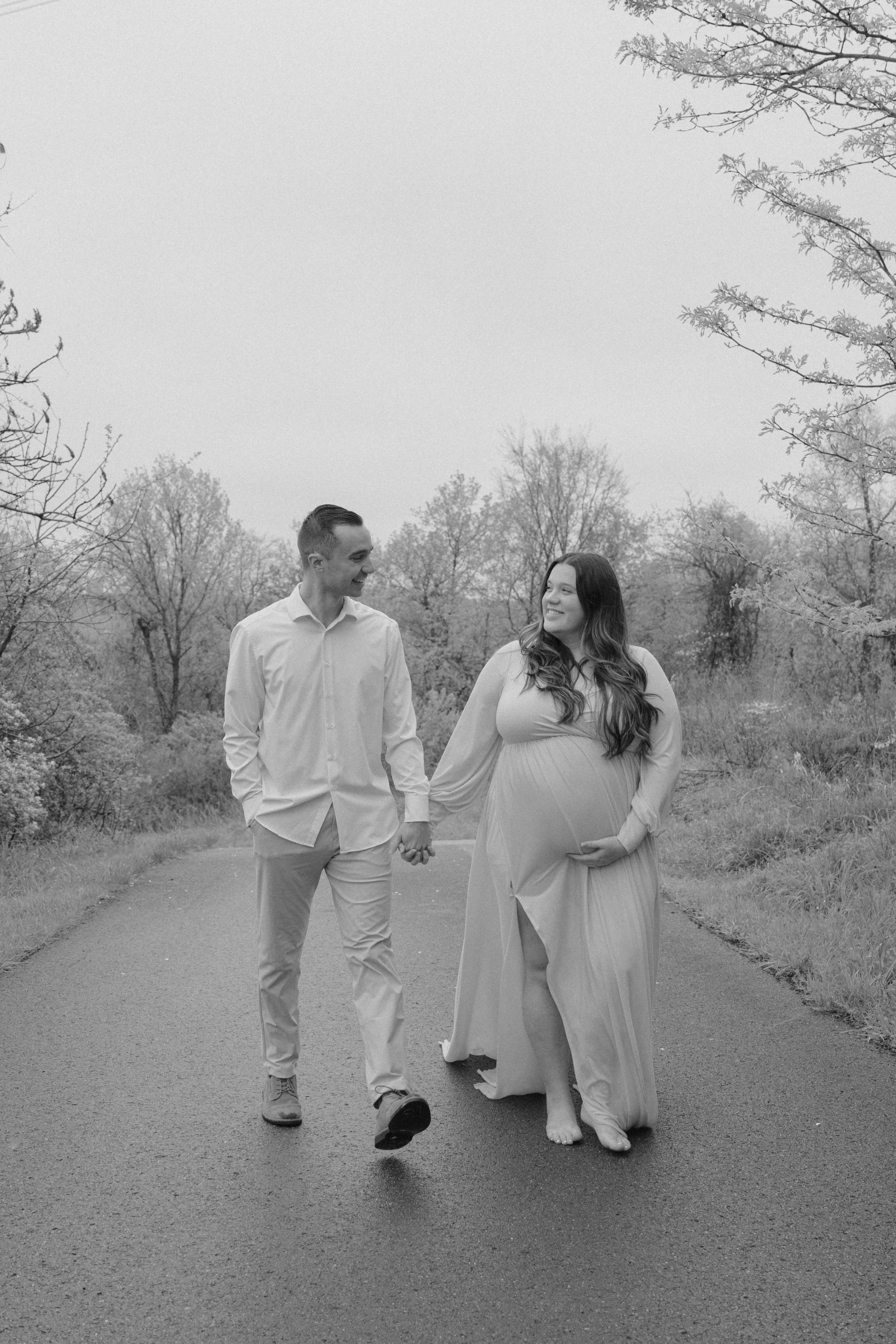 A black and white photo captures a couple walking together on an outdoor path.