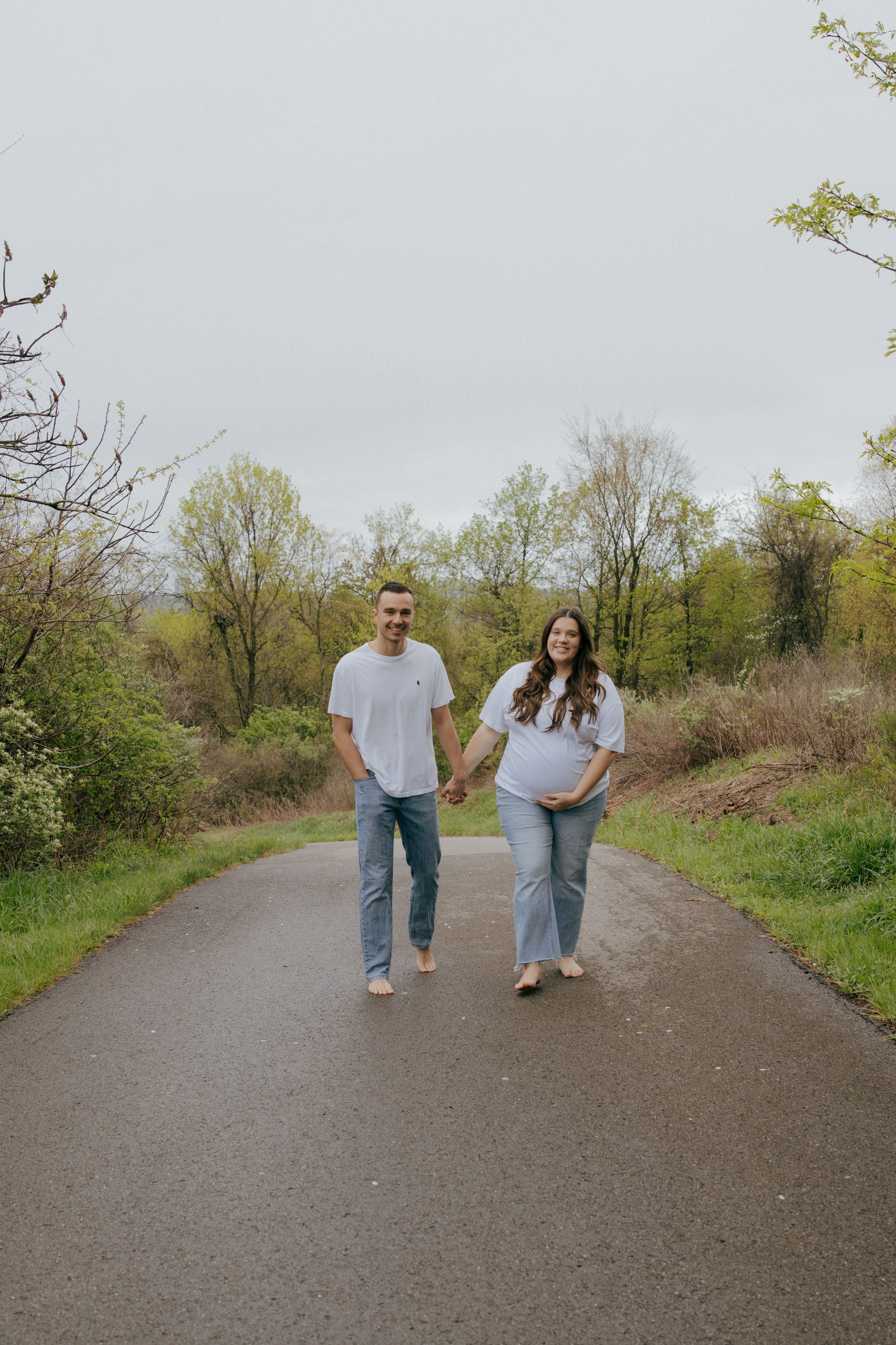 A couple in casual attire strolls down a nature path on a spring day.
