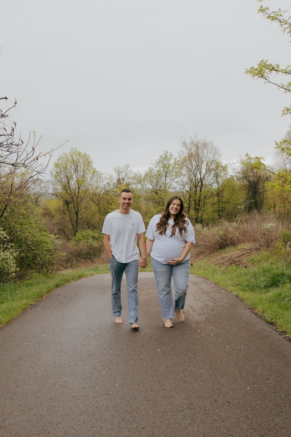 A couple in matching denim and white tops walks together on a dirt path.