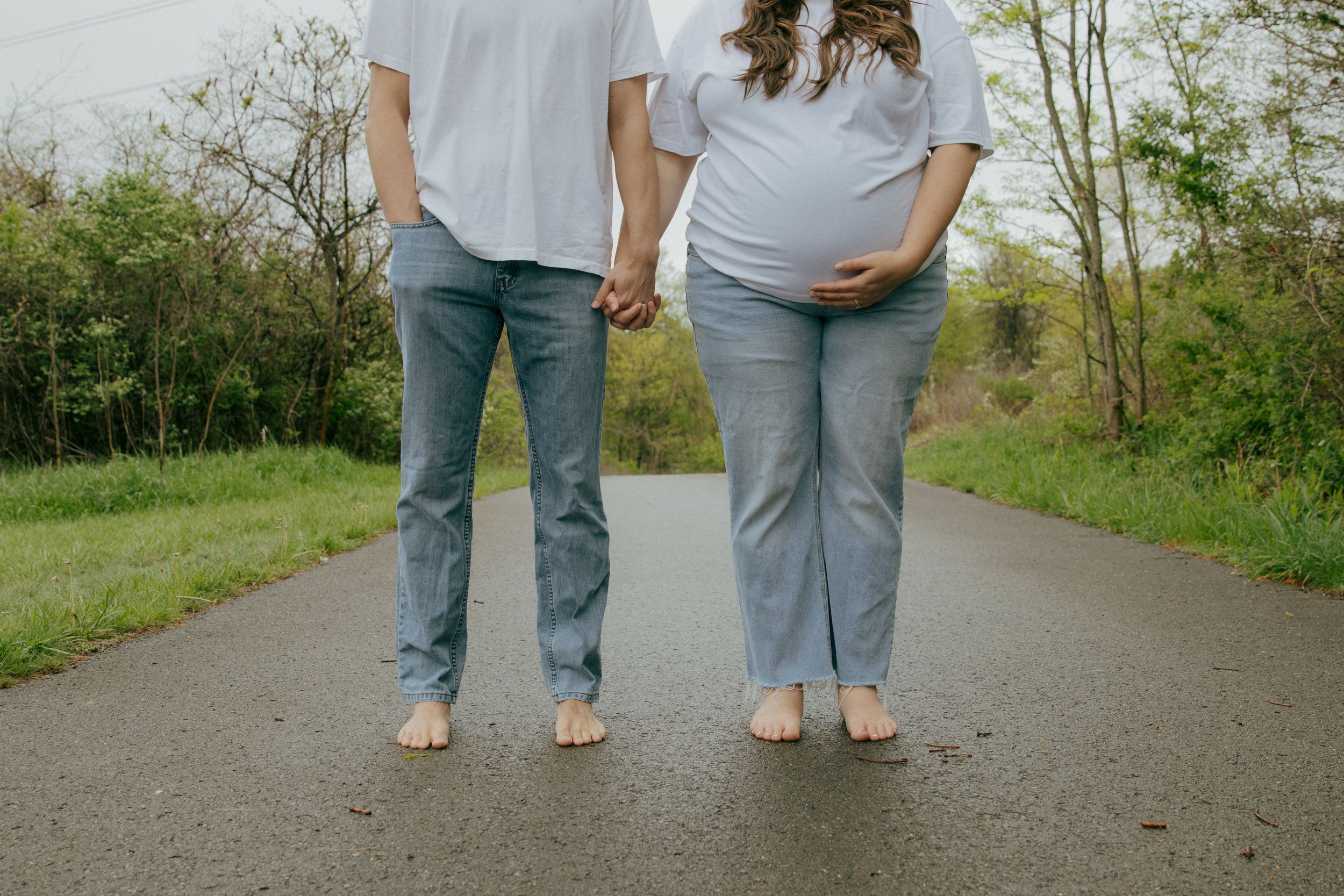 A couple walks together on a tree-lined path wearing coordinated casual outfits.