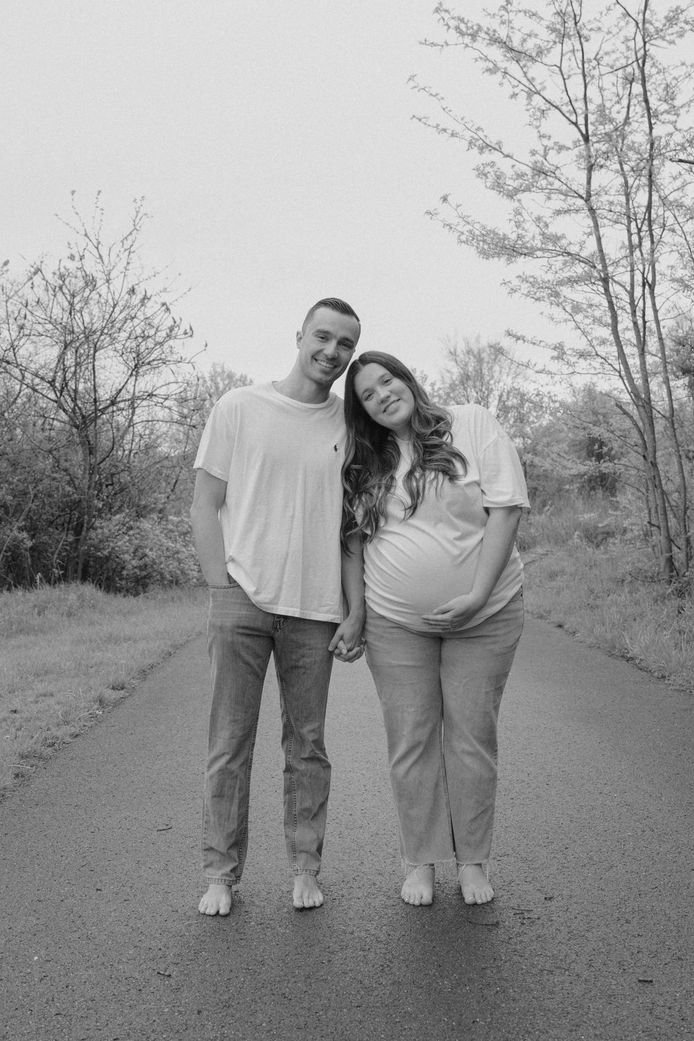 Black and white photo of a couple in casual attire standing close together on a path.