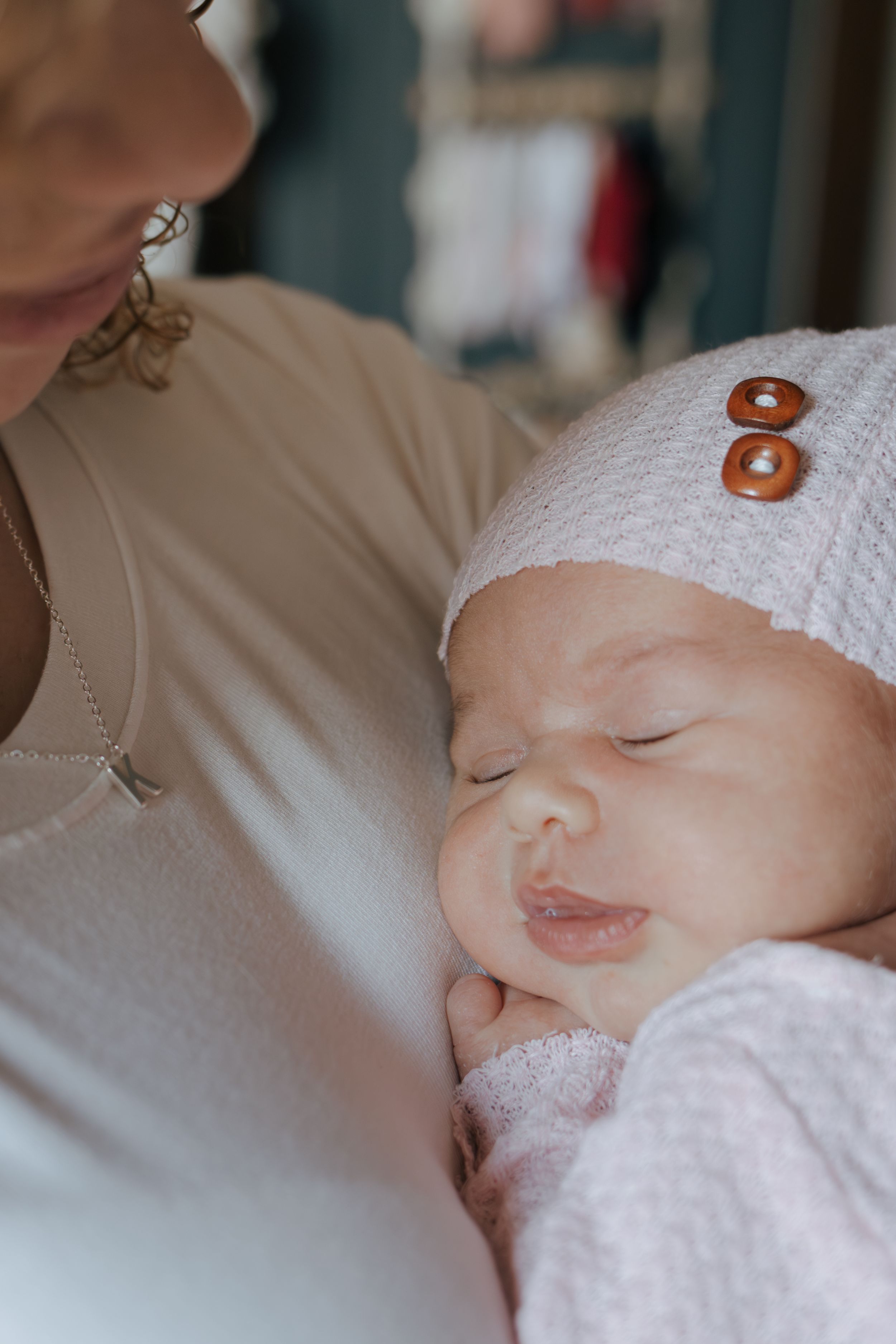 Peaceful sleeping baby in white hat and pink outfit smiles softly.