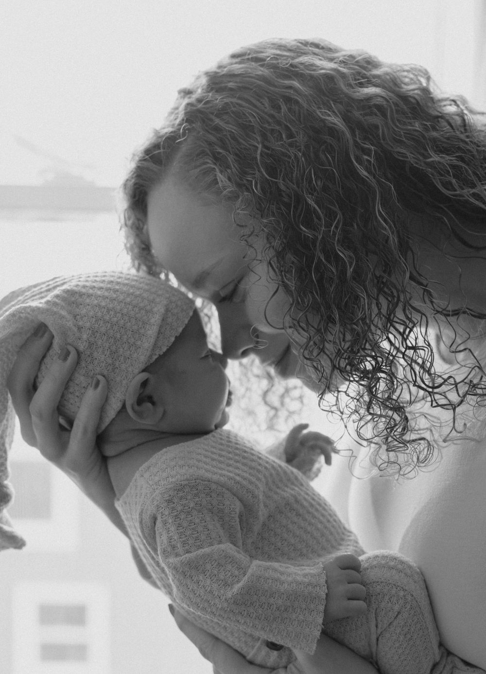 Black and white image of tender moment between caregiver and baby.