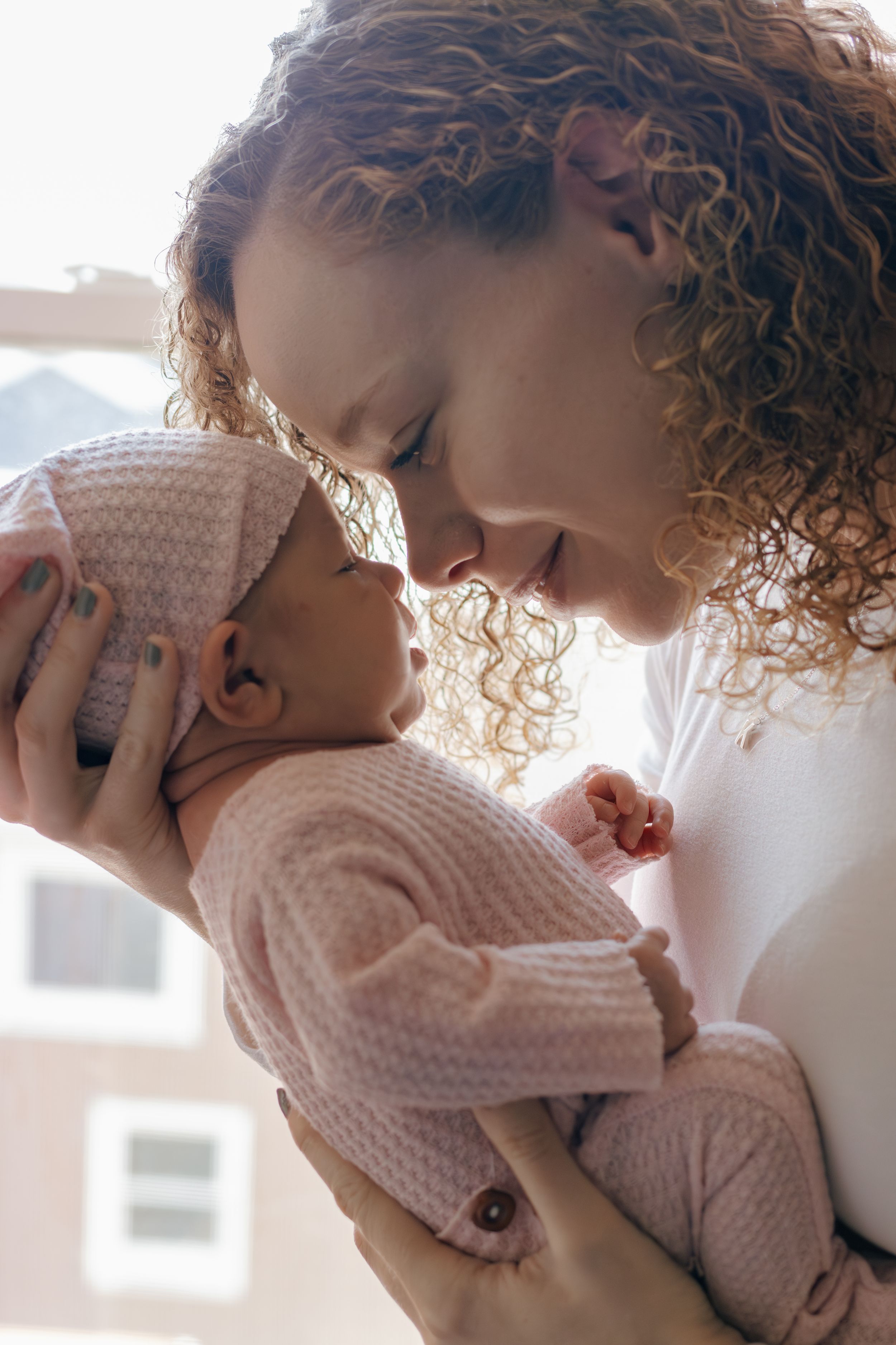 Intimate portrait of parent and baby sharing affectionate moment in natural light.