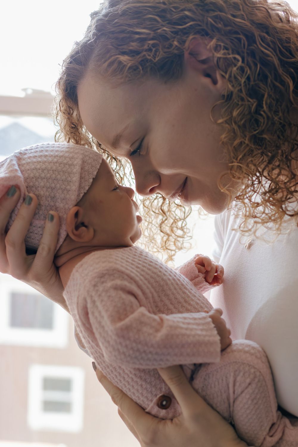 Intimate portrait of parent and baby sharing affectionate moment in natural light.