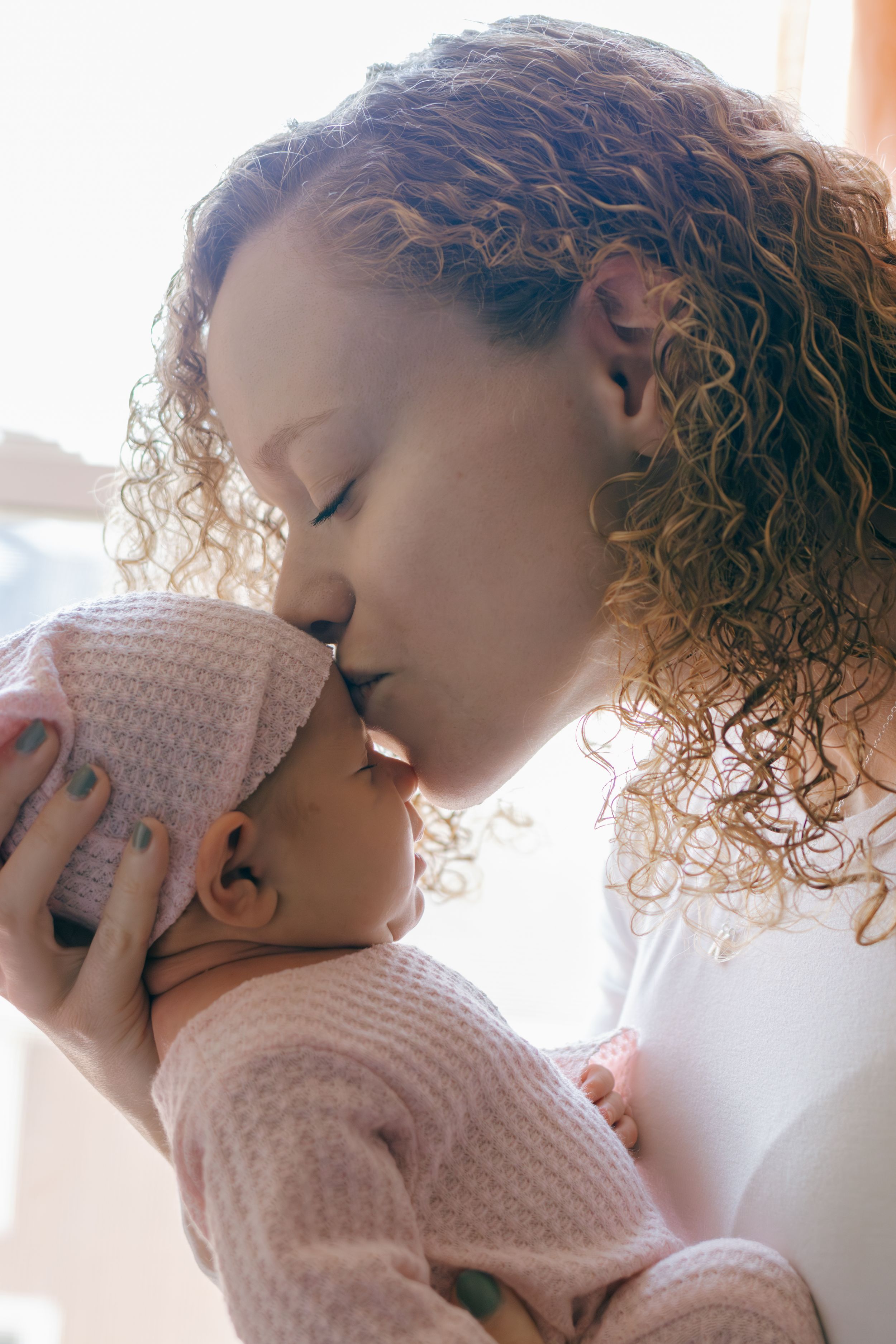 Sweet bonding moment between parent and infant in soft pink knitwear.