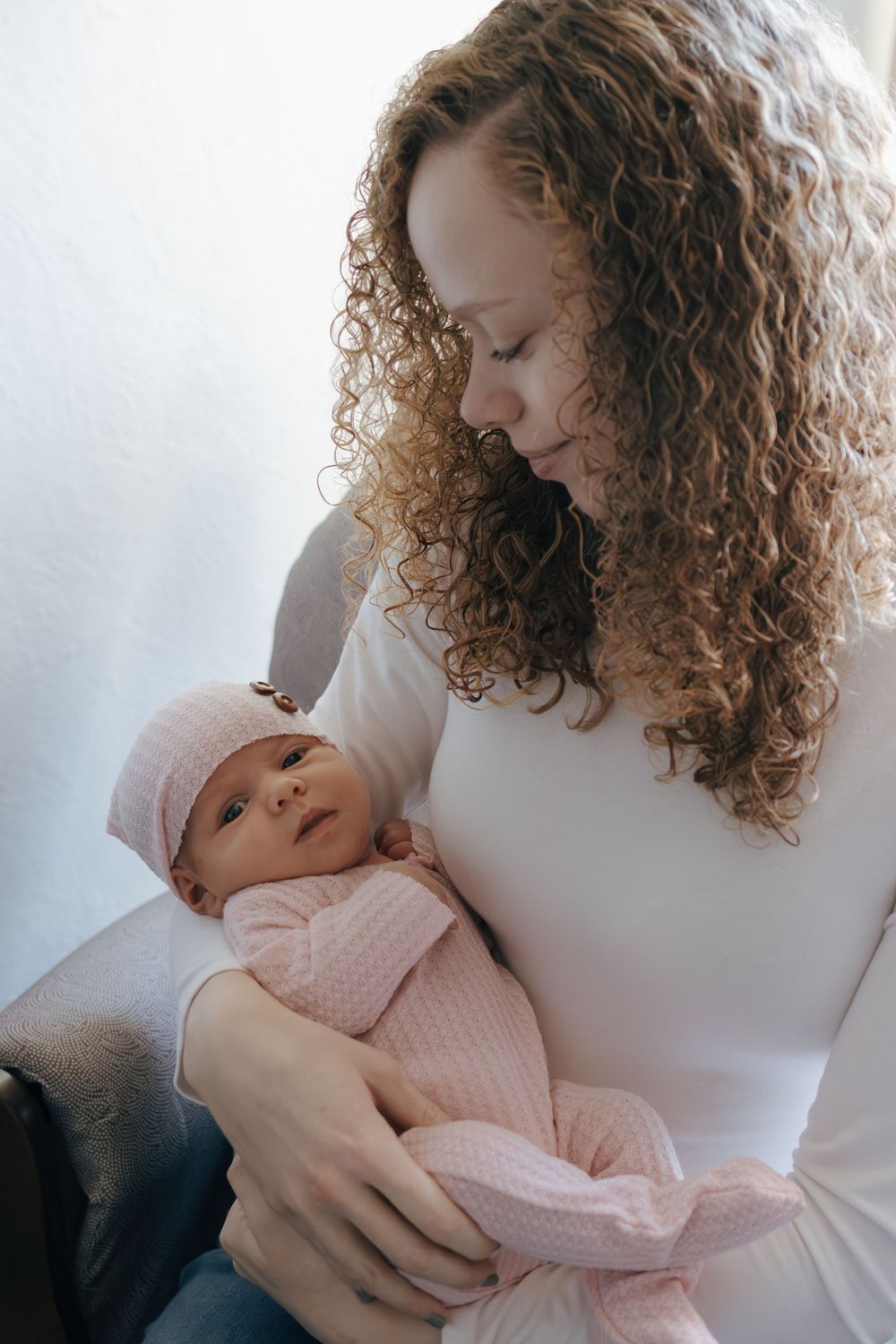 Tender moment between parent and baby wearing pink knit clothing.