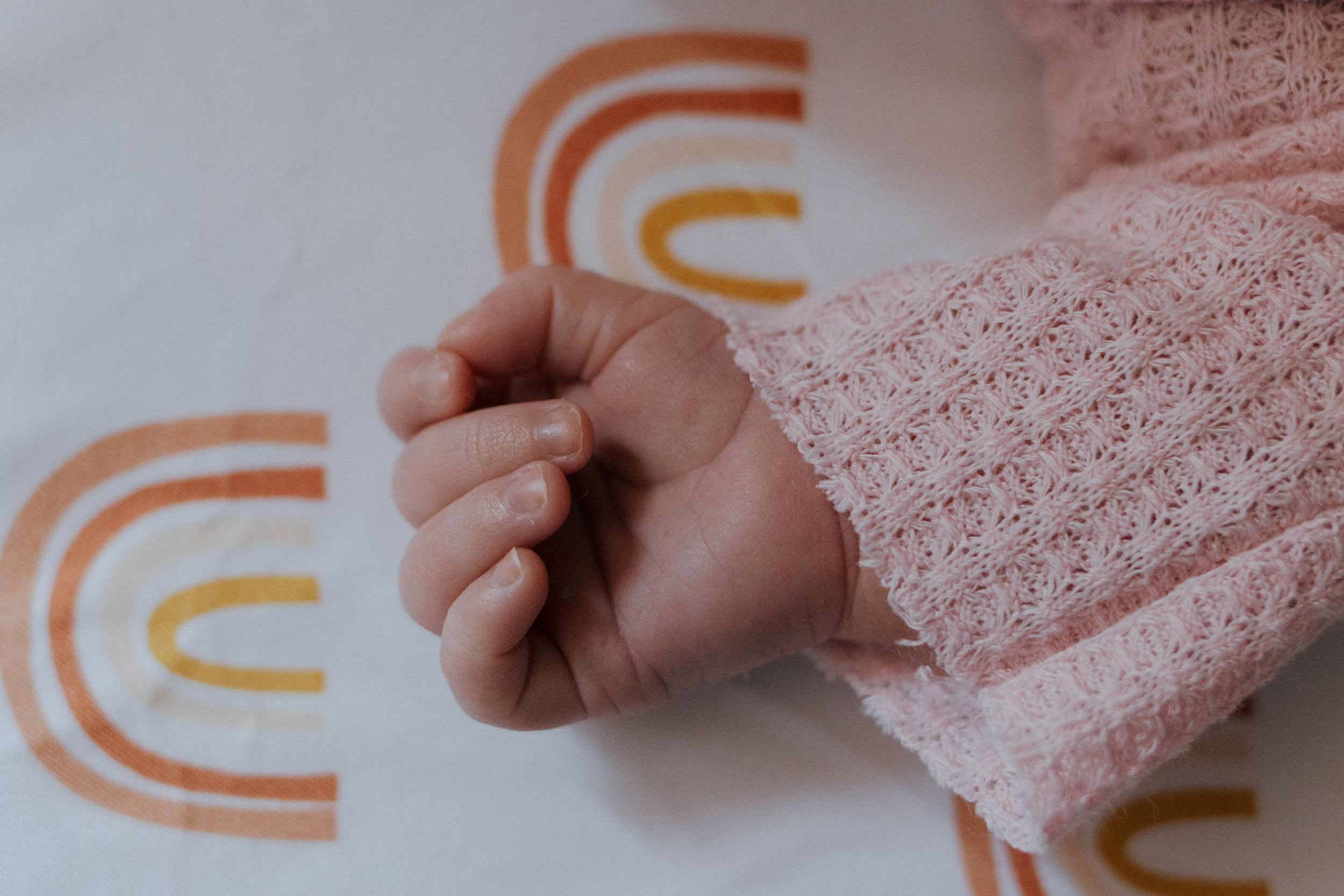 Close-up view of orange curved pattern designs on white background with soft pink fabric visible.