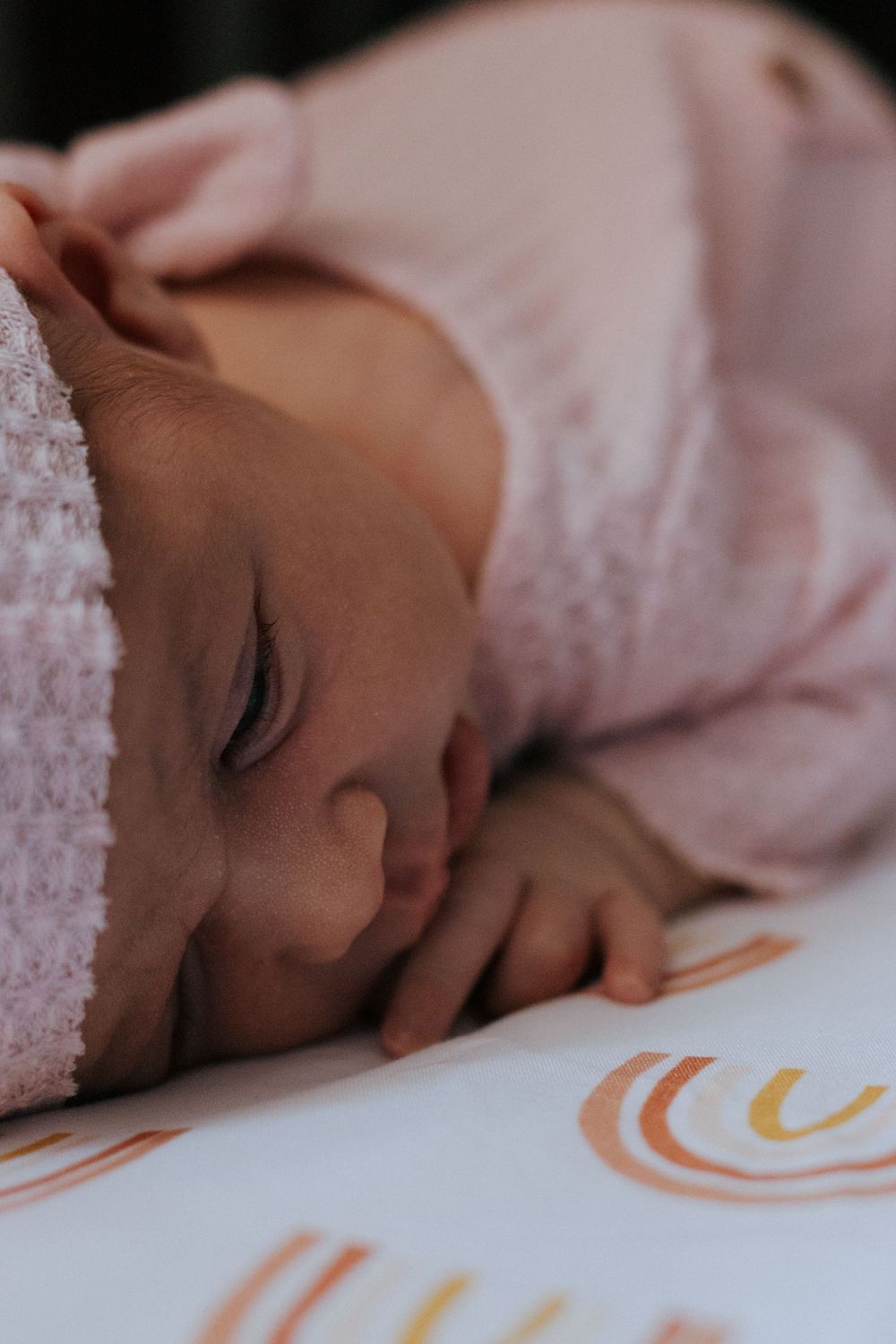 Close-up detail of baby sleeping on white surface with orange curved designs.
