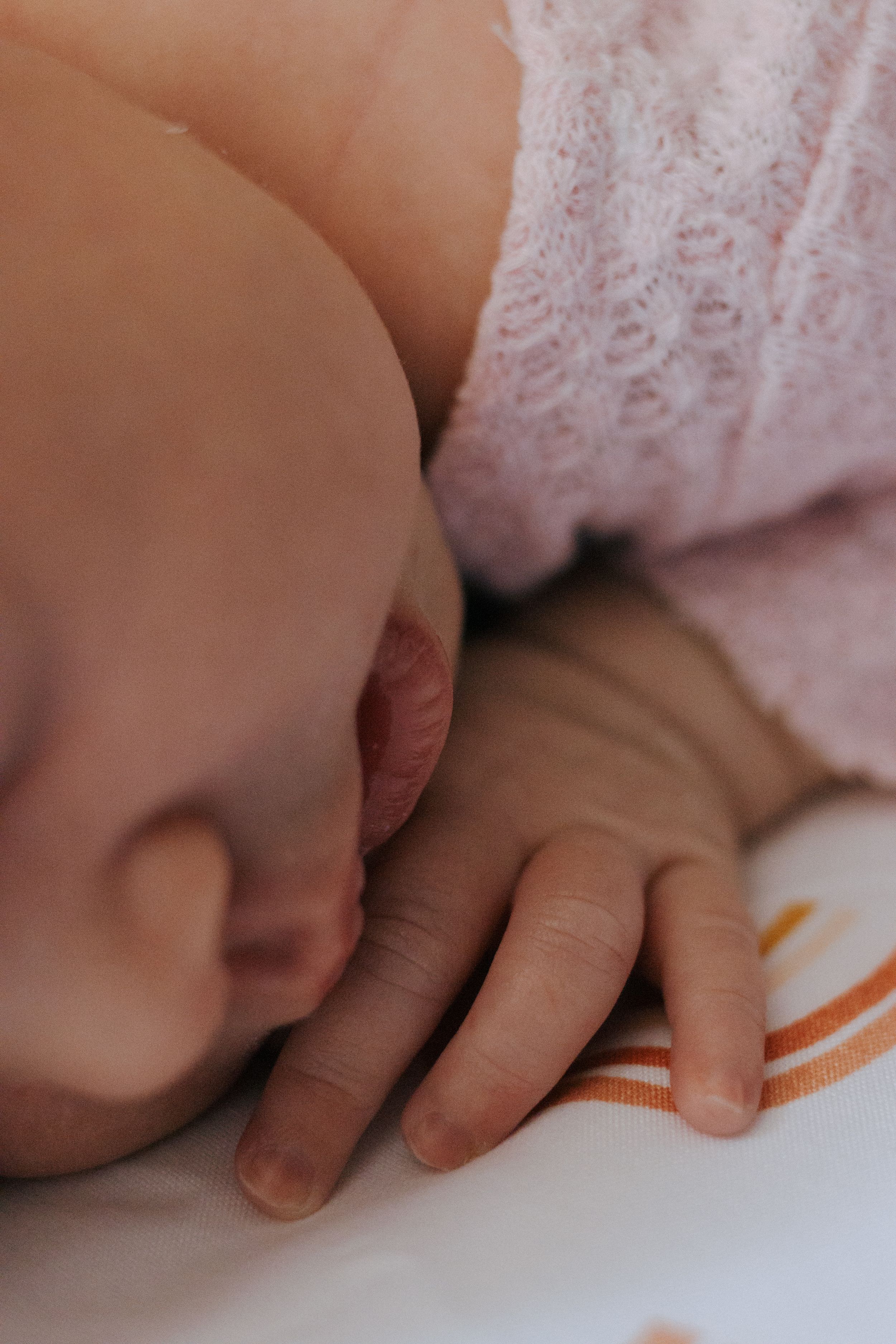 Tiny hand resting on white surface decorated with orange curved patterns.