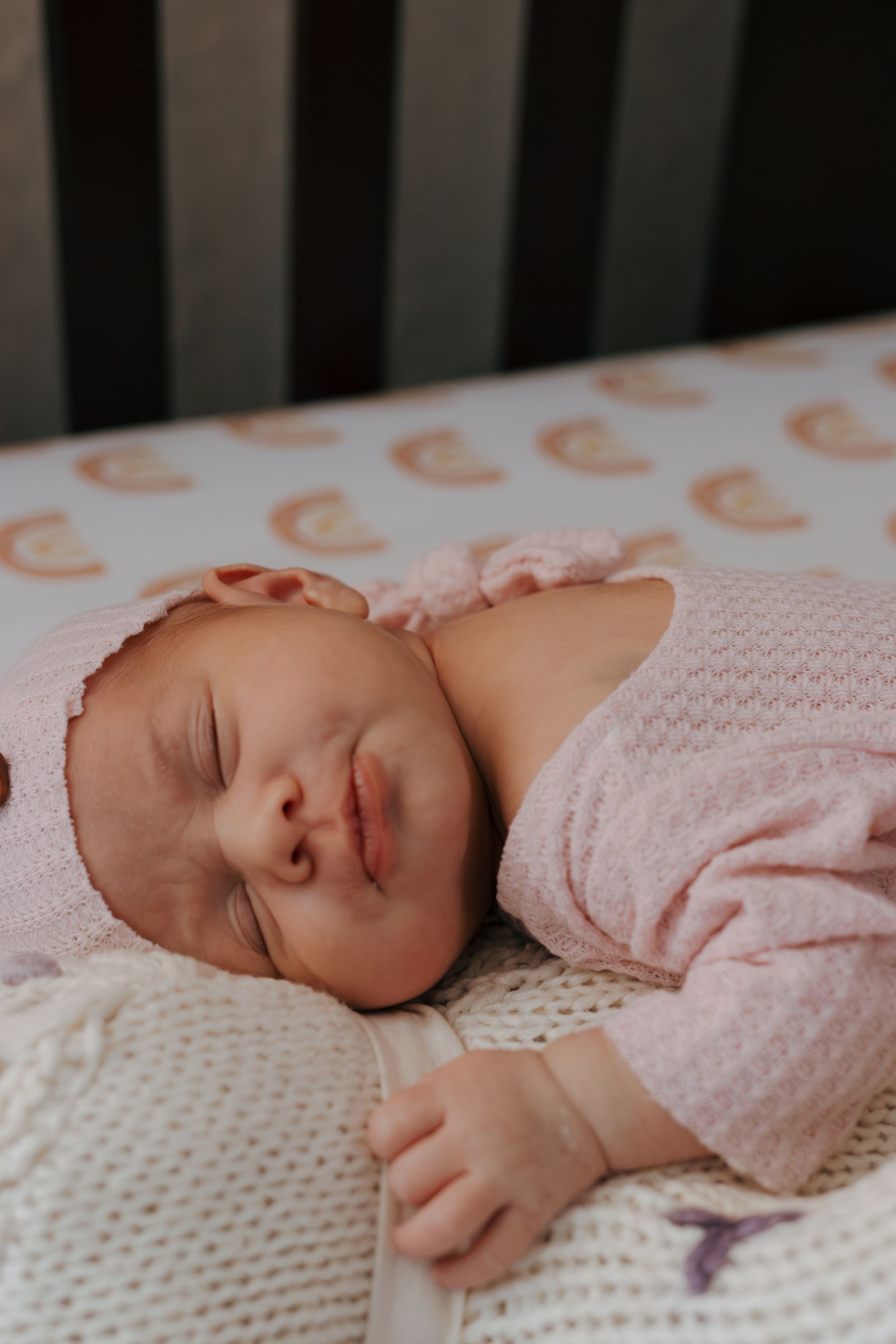 Infant napping on textured white blanket with orange pattern visible in background.
