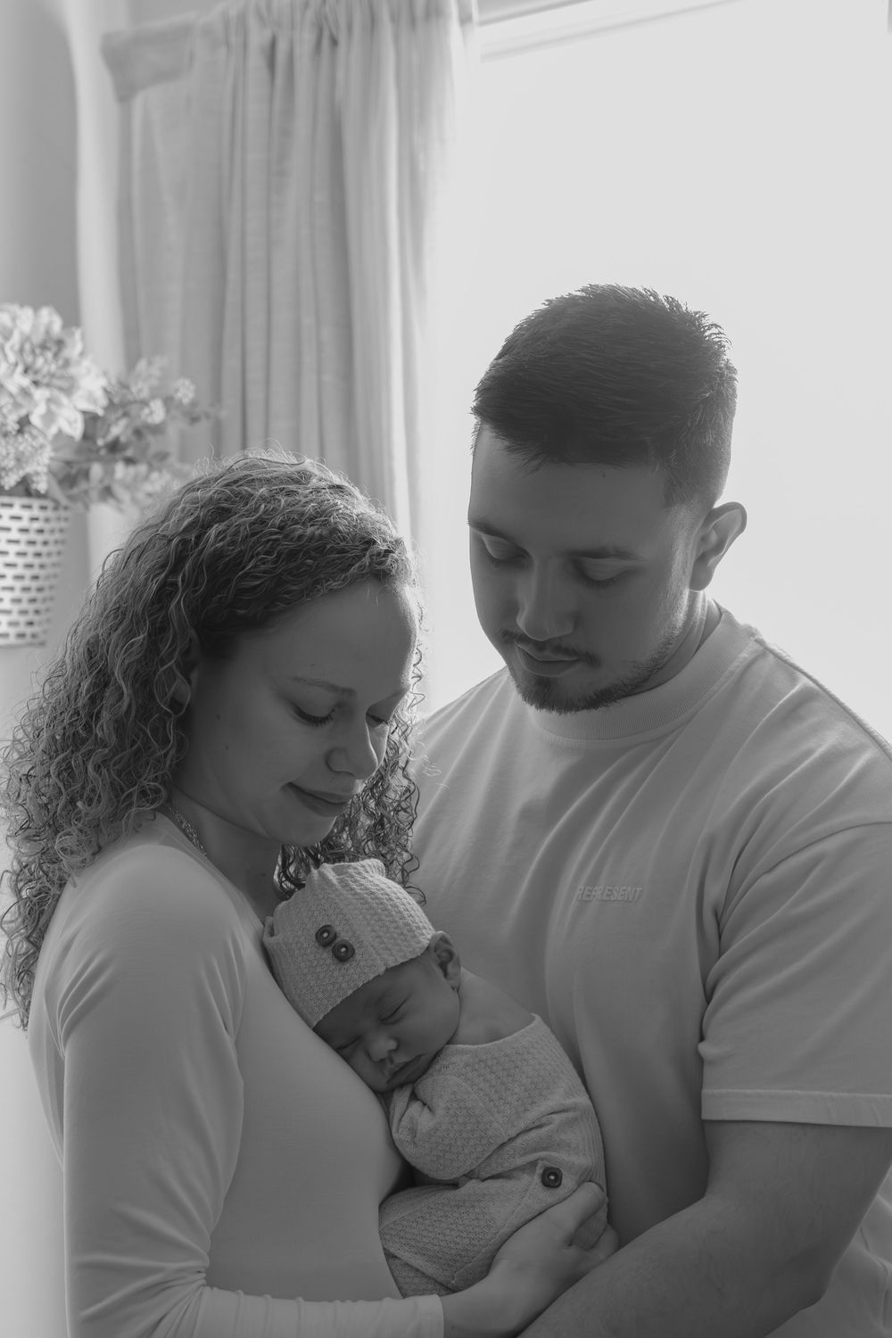 Black and white portrait of parents sharing intimate moment with their newborn baby.