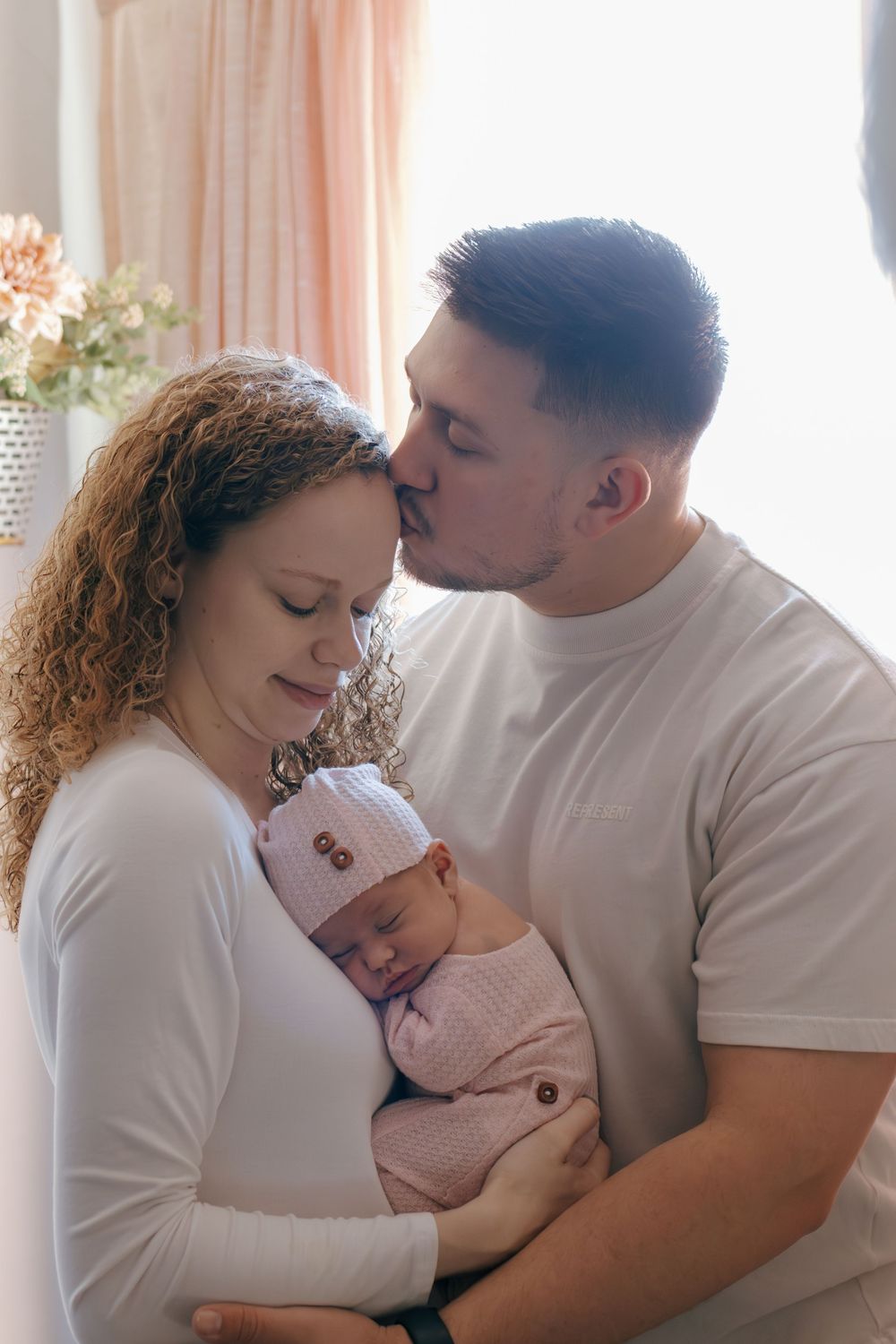 Loving parents share tender moment with their newborn baby in peaceful home setting.