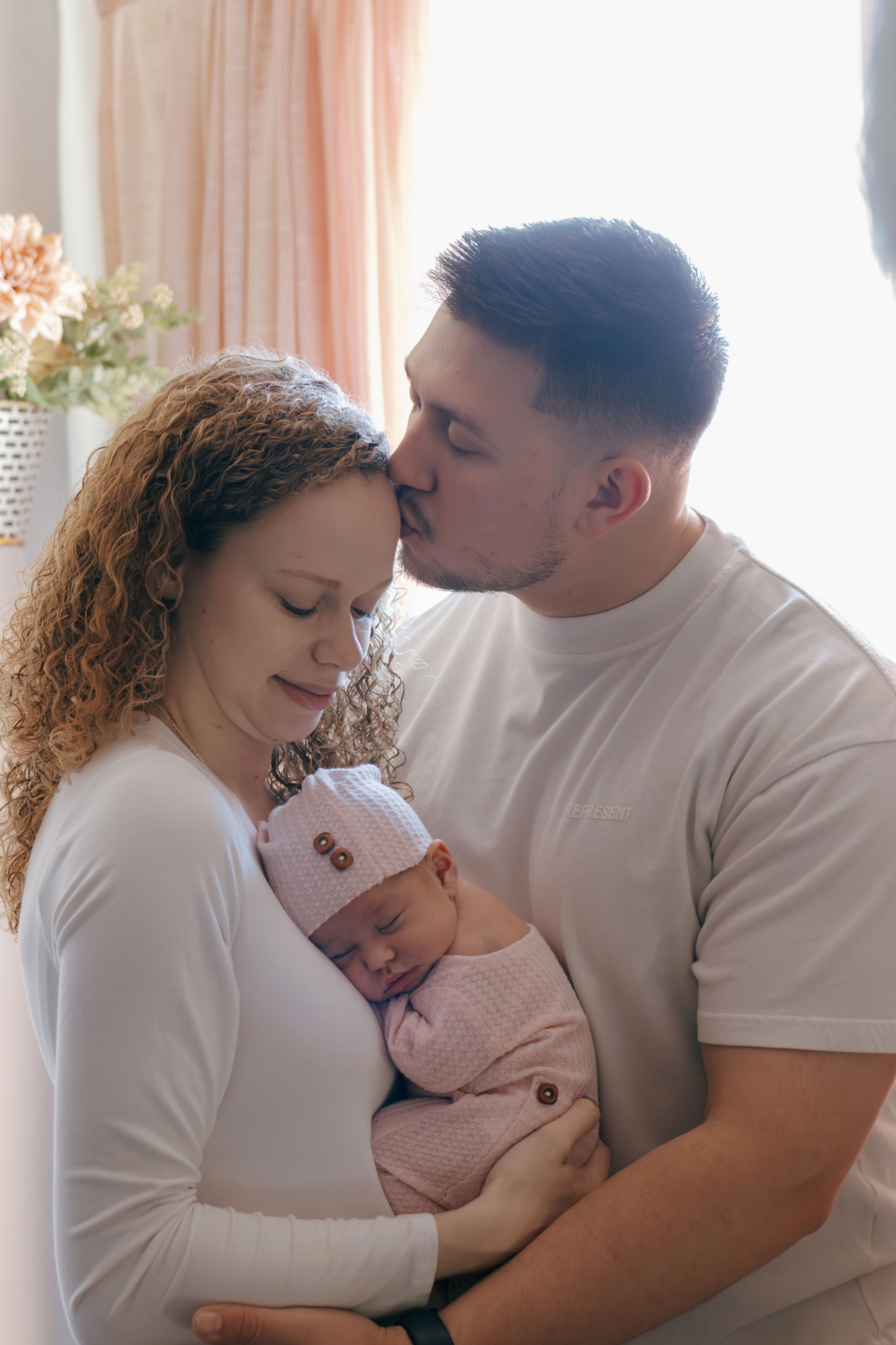 Loving parents share tender moment with their newborn baby in peaceful home setting.