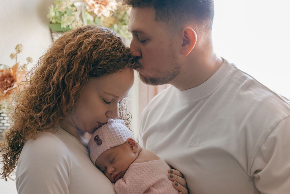 Candid family portrait series showing intimate moments between parents and newborn.