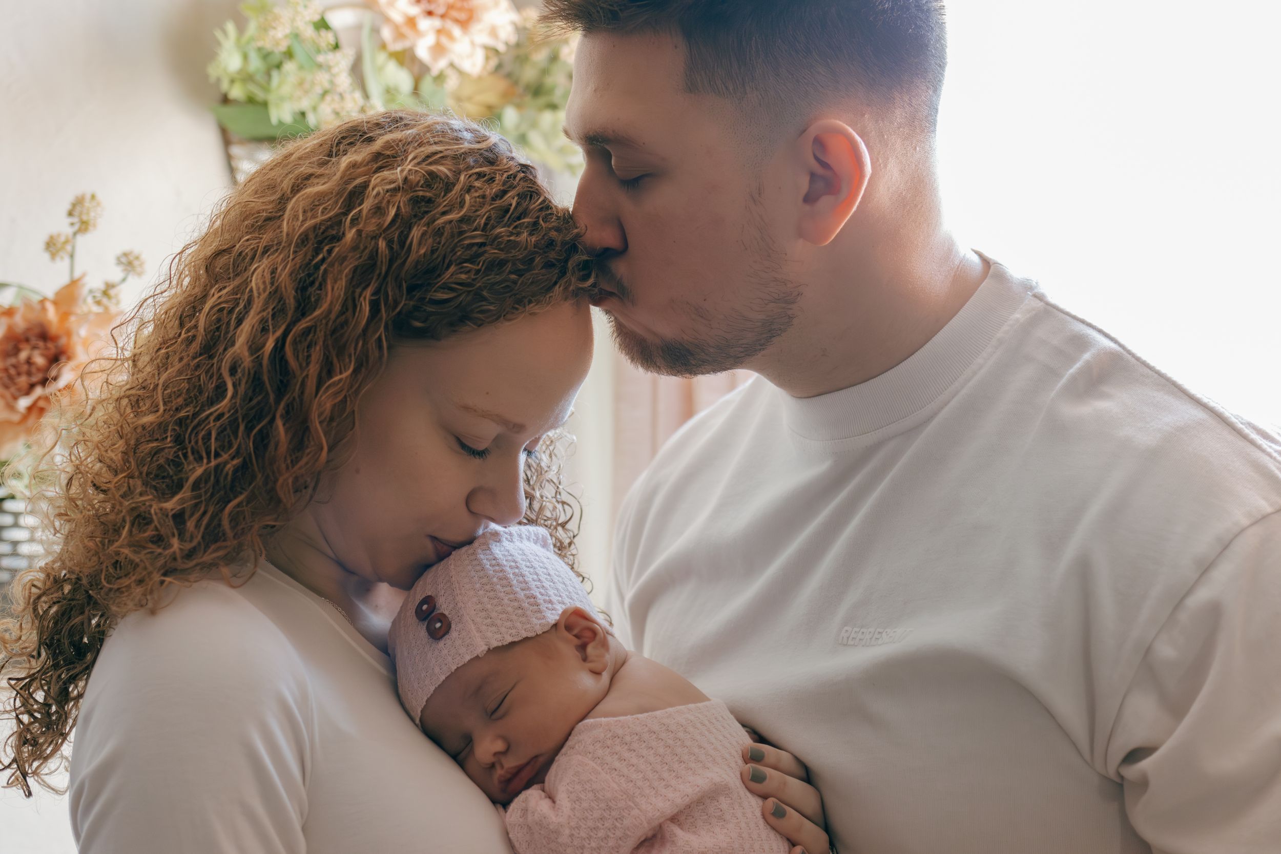 Candid family portrait series showing intimate moments between parents and newborn.
