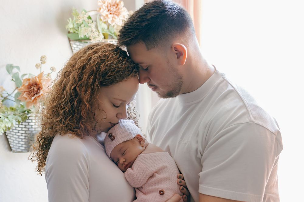 Natural light family portraits showing tender moments between parents and baby.