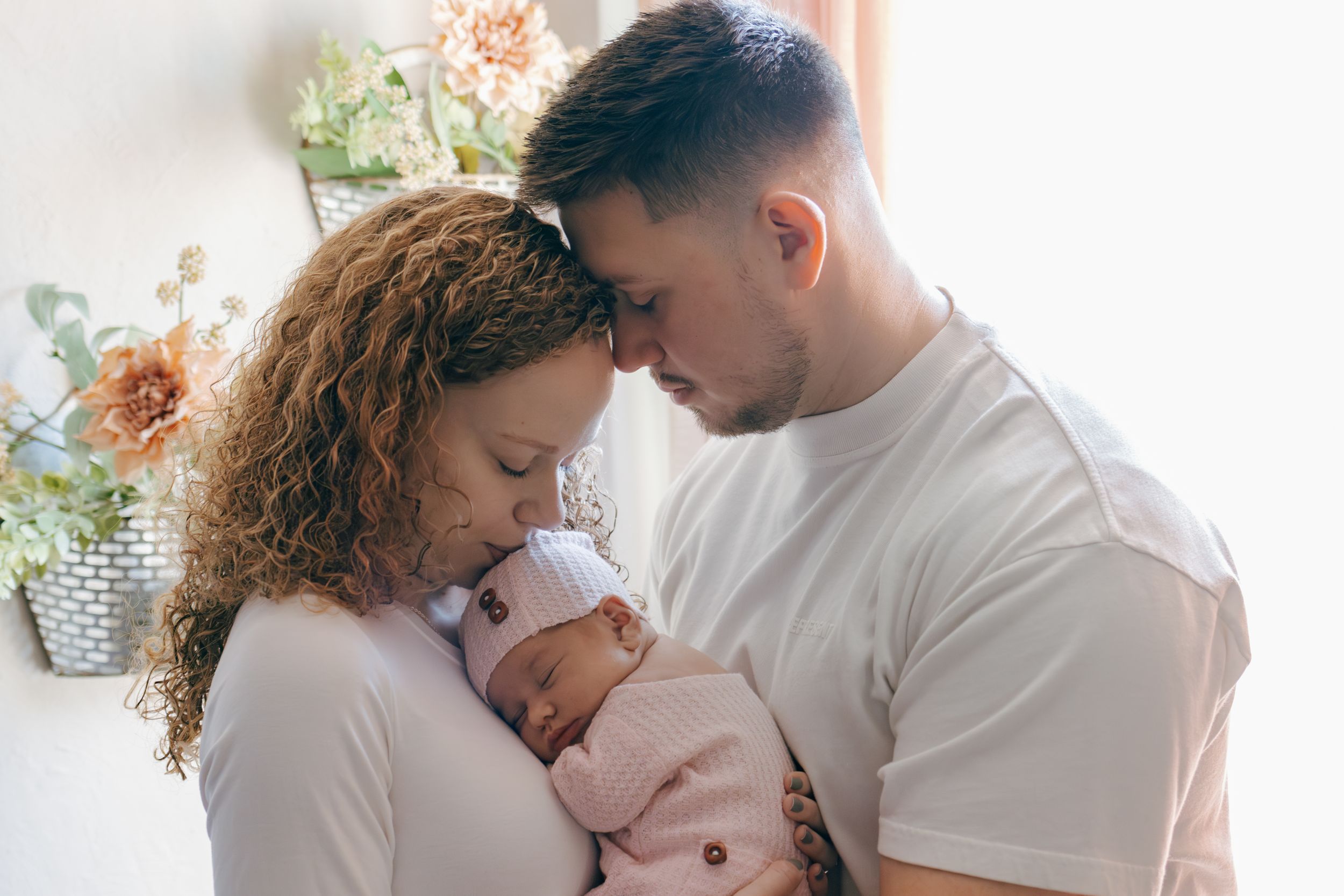 Natural light family portraits showing tender moments between parents and baby.