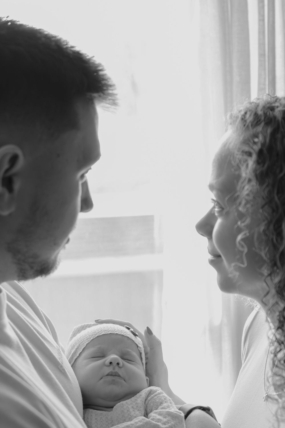 Black and white portrait of a sleeping infant being held by caregivers.