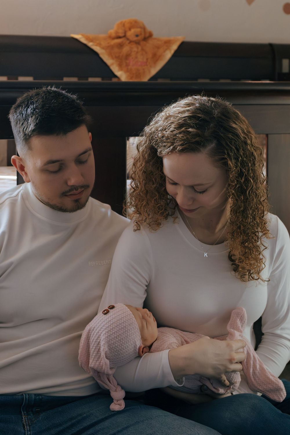 Tender moment between couple wearing white tops in nursery setting.