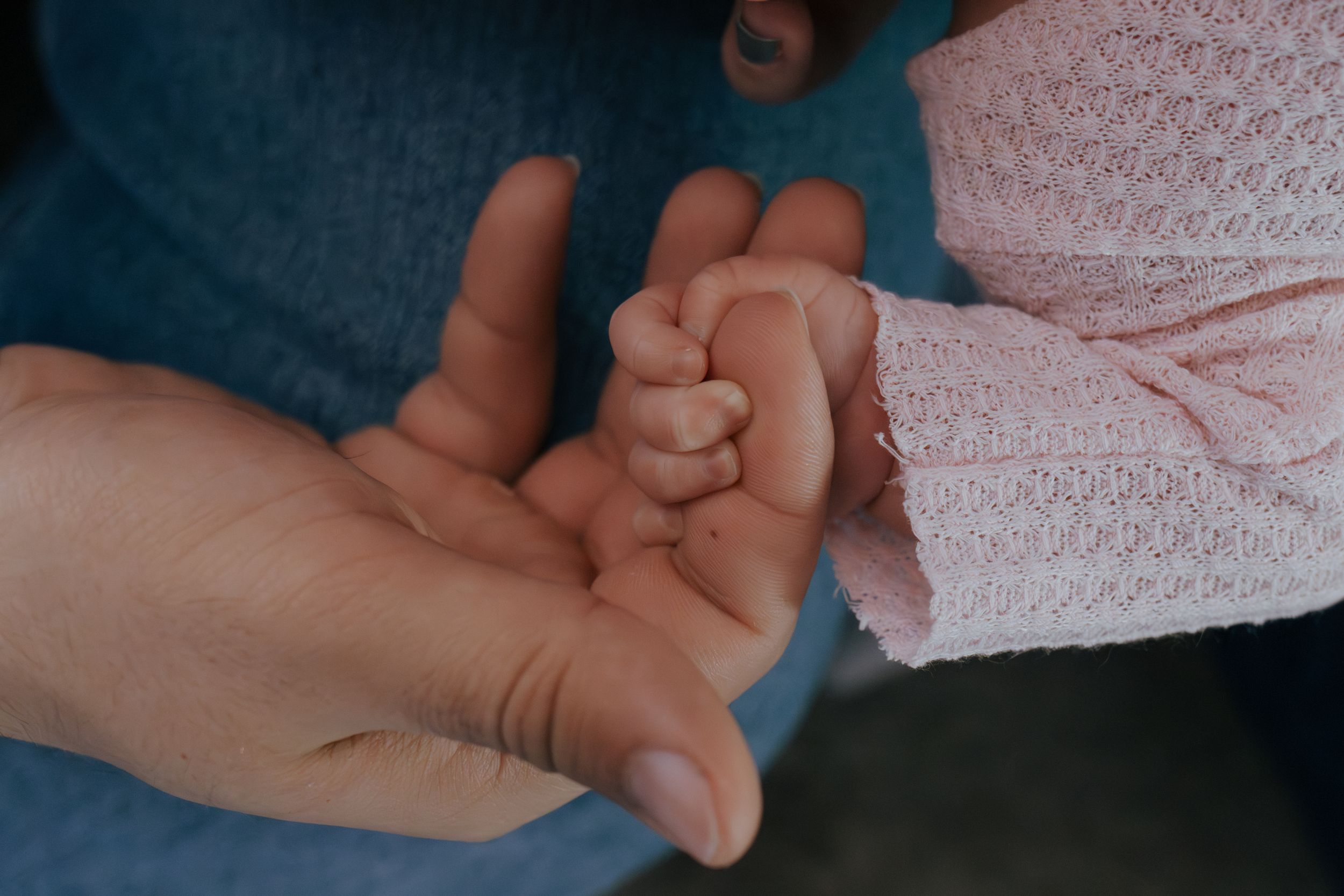 Close-up of tiny baby feet being gently held in adult hands.