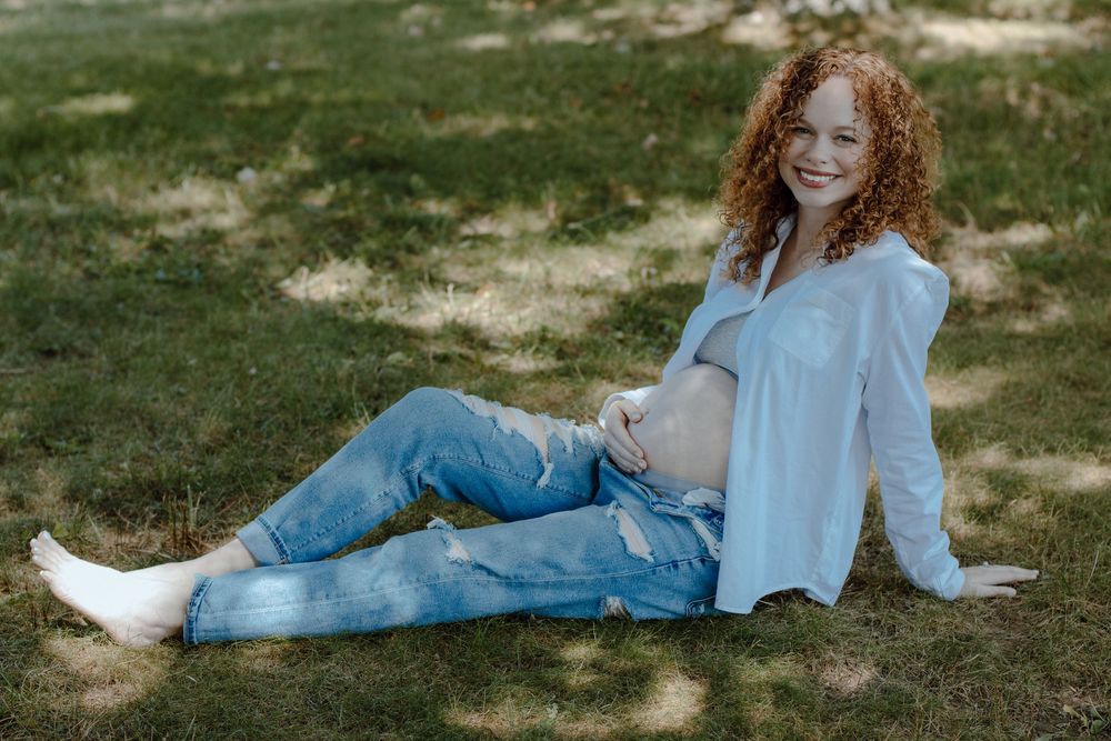 Person in white shirt and jeans lying on grass during sunny day.