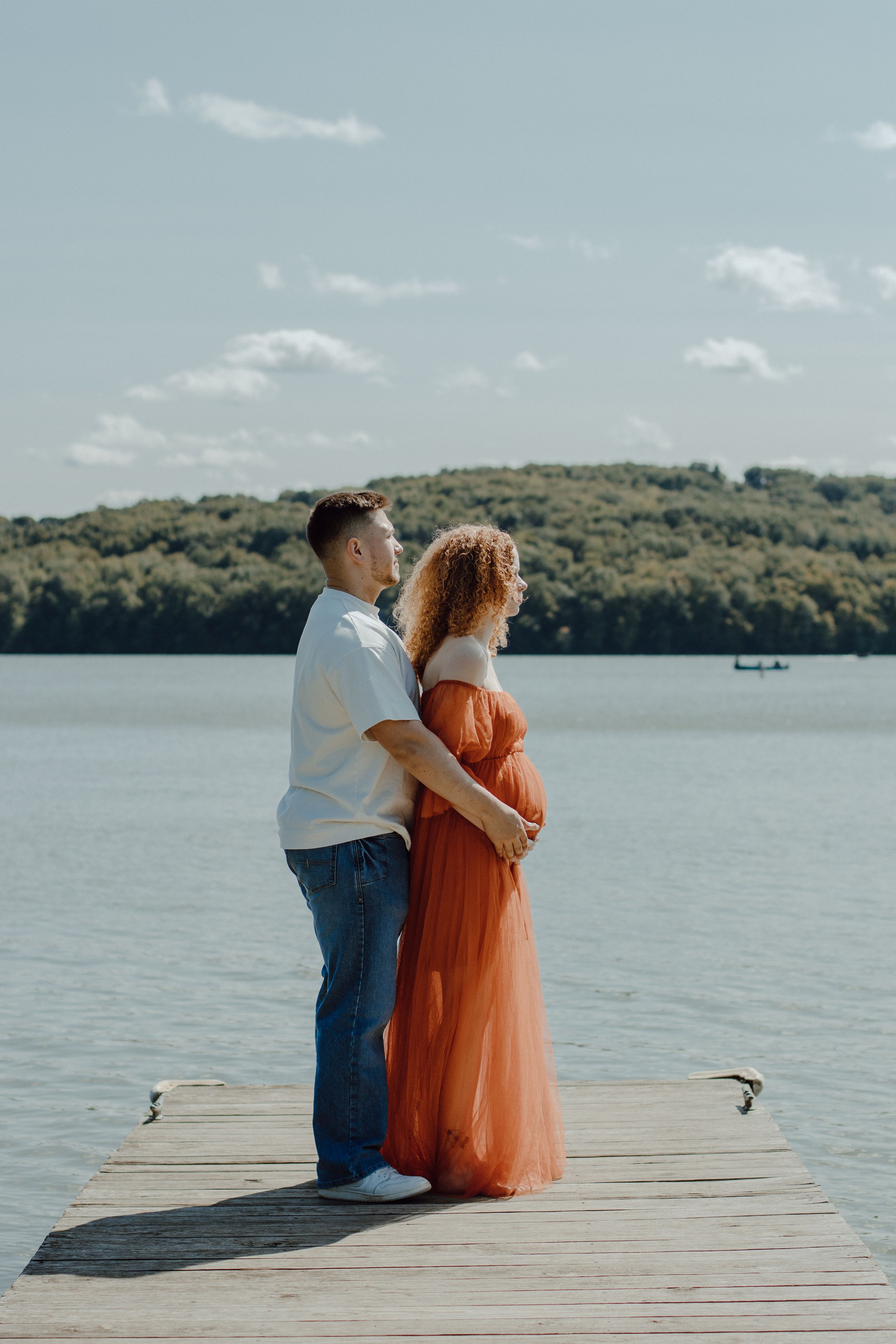 Couple sharing intimate moment on wooden dock by scenic lake.