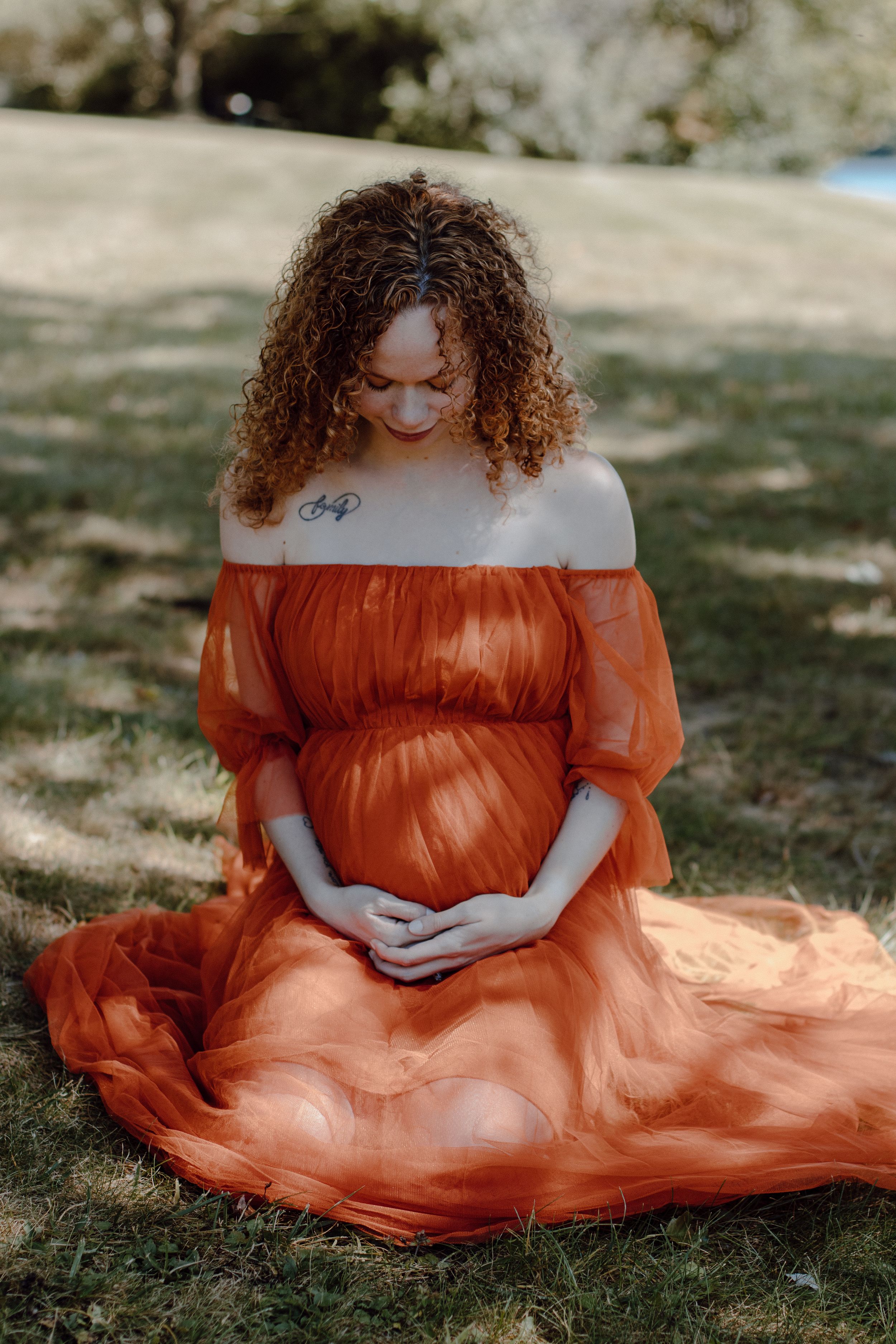 Ethereal maternity photo featuring a flowing orange dress in a natural outdoor setting.