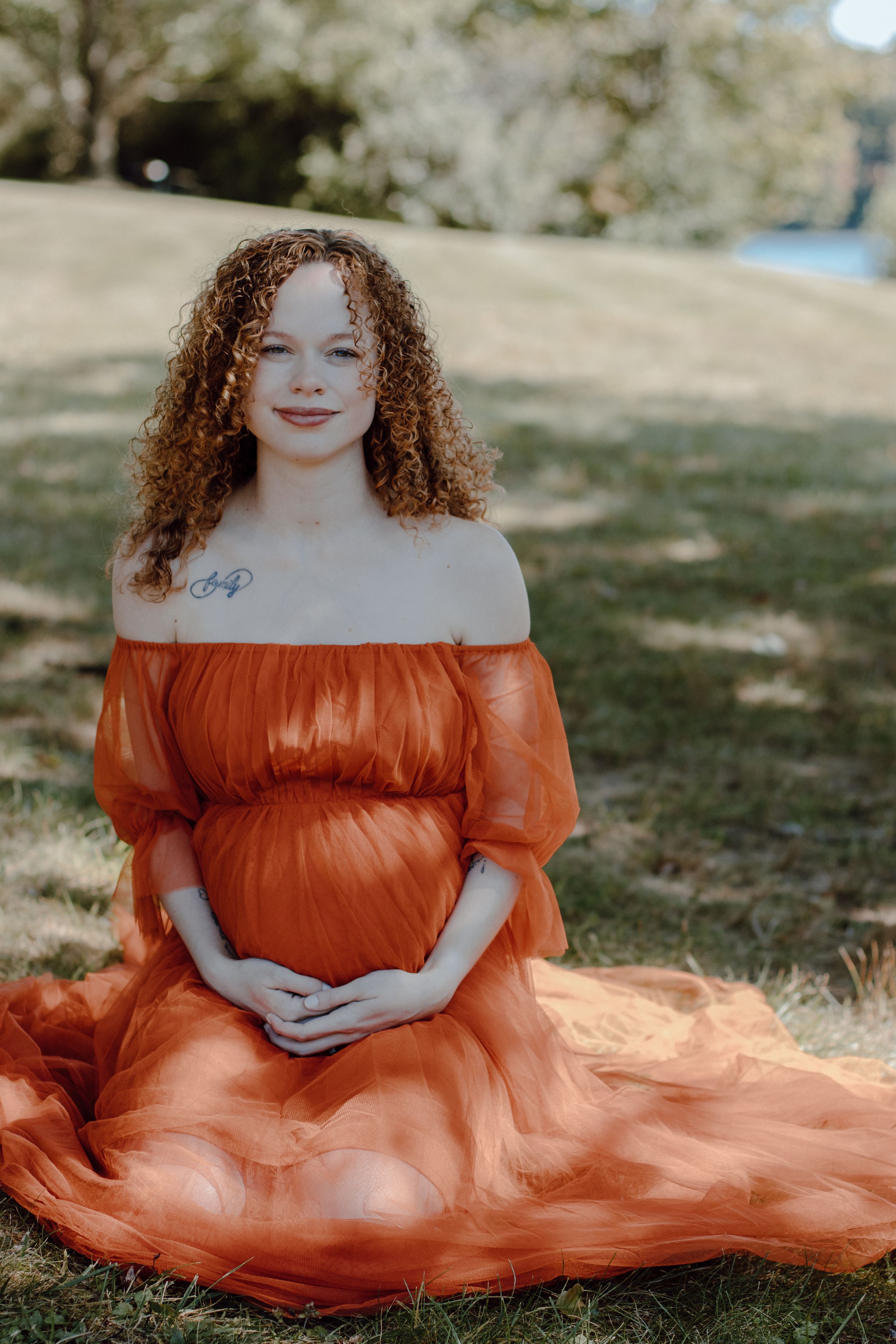 Dreamy outdoor portrait with a flowing terracotta-colored dress against natural scenery.