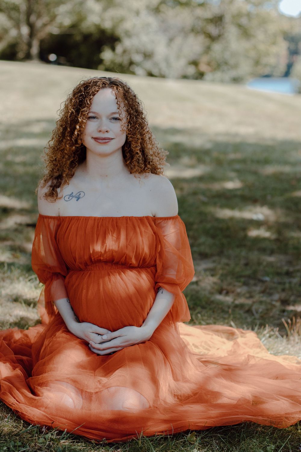 Dreamy outdoor portrait with a flowing terracotta-colored dress against natural scenery.