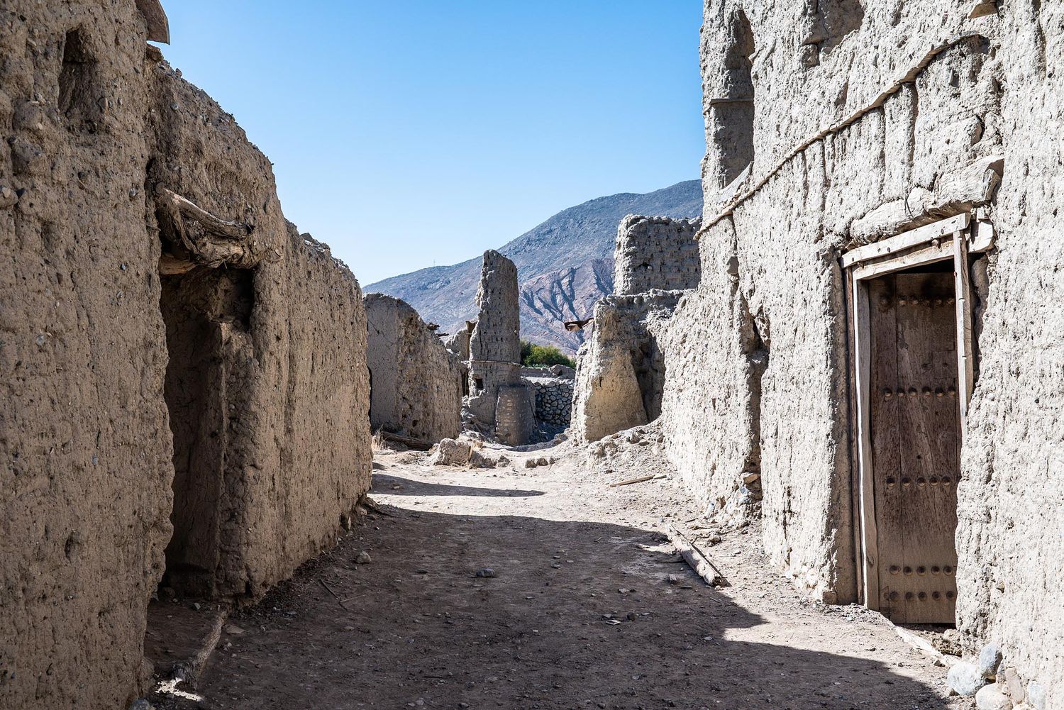 Ancient stone ruins of narrow alleyways and doorways line a winding path through a historic mountain village.