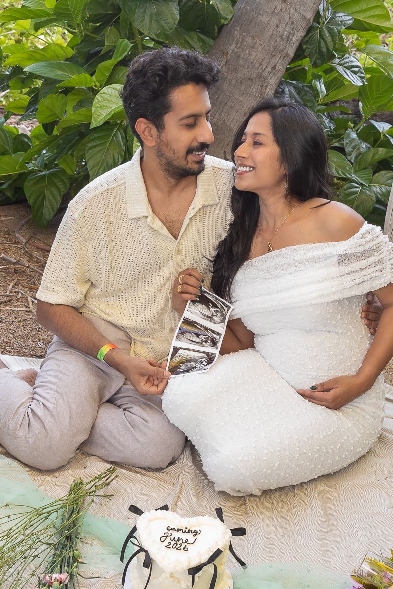 A couple in white and beige outfits share romantic moments while relaxing outdoors on a sunny day.