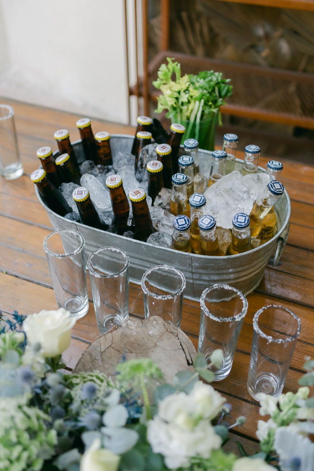 Glass ice bucket filled with beer bottles and floral decorations at an elegant event.