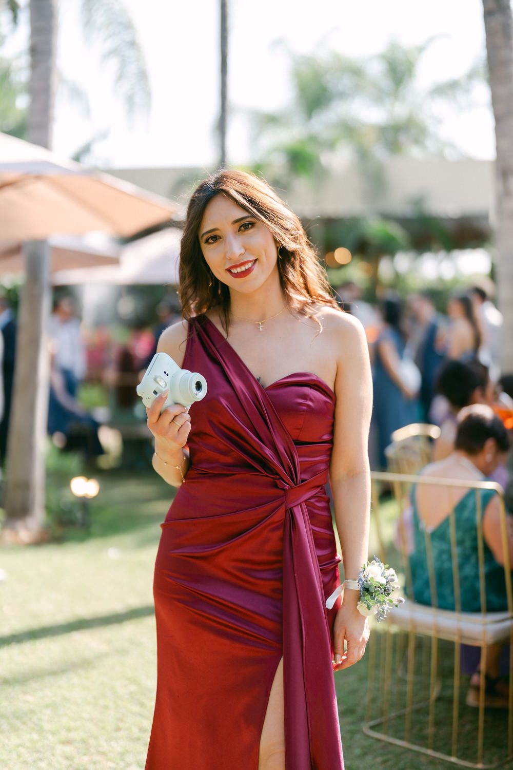 Bridesmaids wearing burgundy dresses pose together at an outdoor wedding venue.