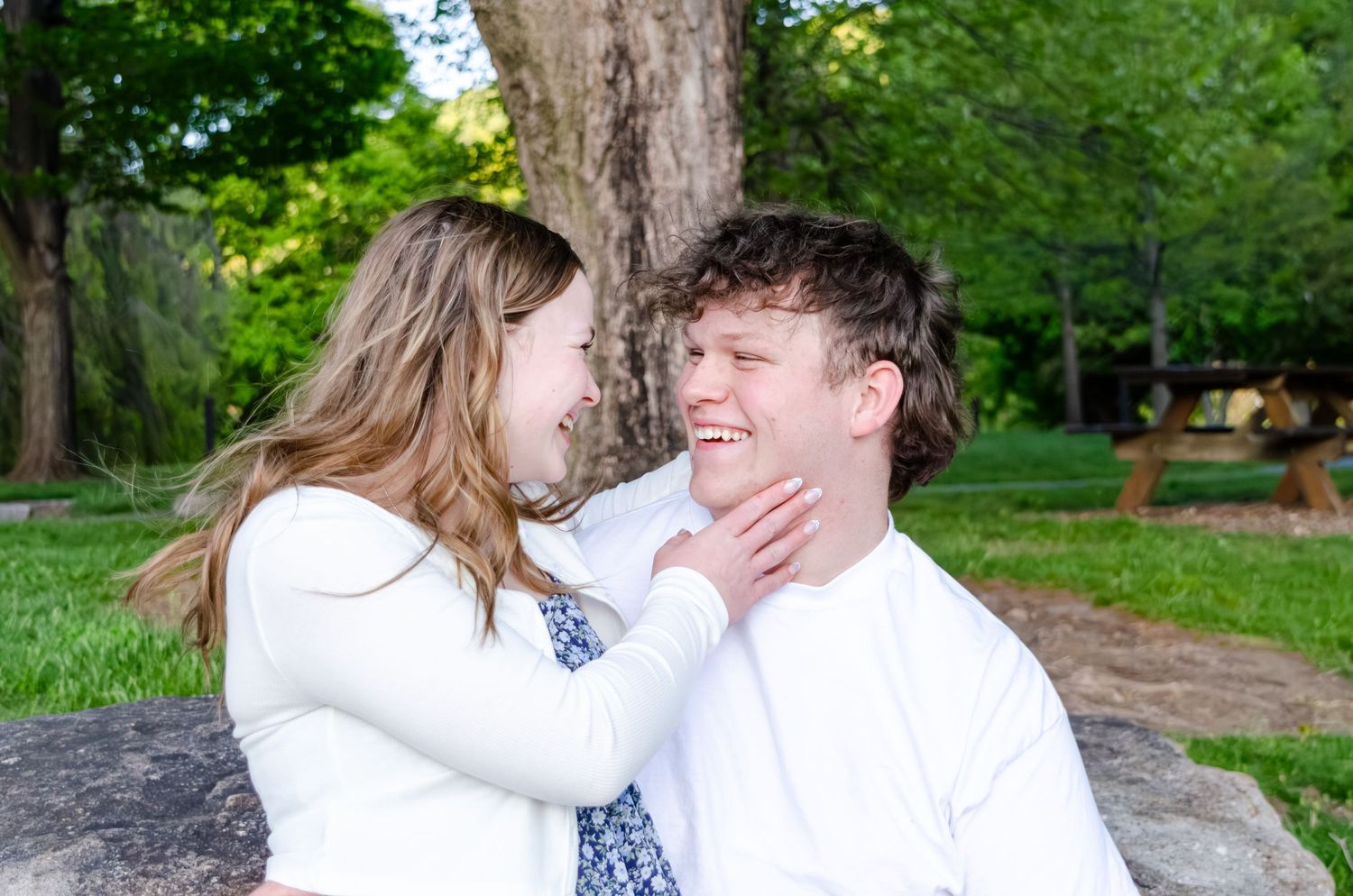 Couple takes romantic photos on a wooden boardwalk by a lake during springtime.