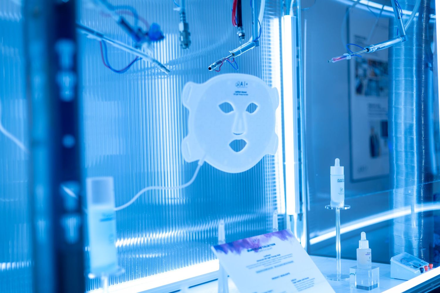 White LED face mask displayed in a blue-lit futuristic skincare technology exhibit.