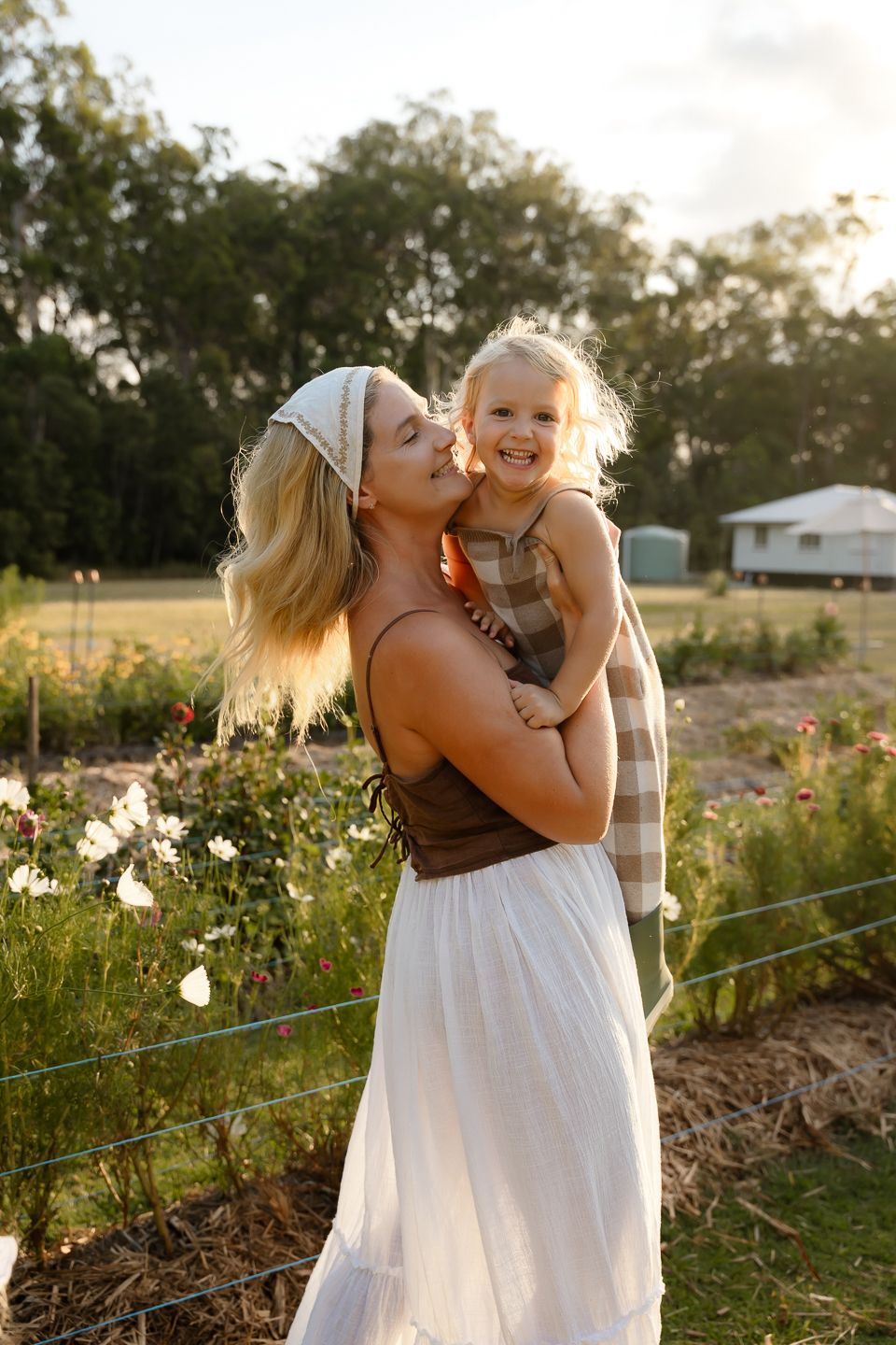 A heartwarming sunset scene in a field with wildflowers and golden light streaming through the trees.